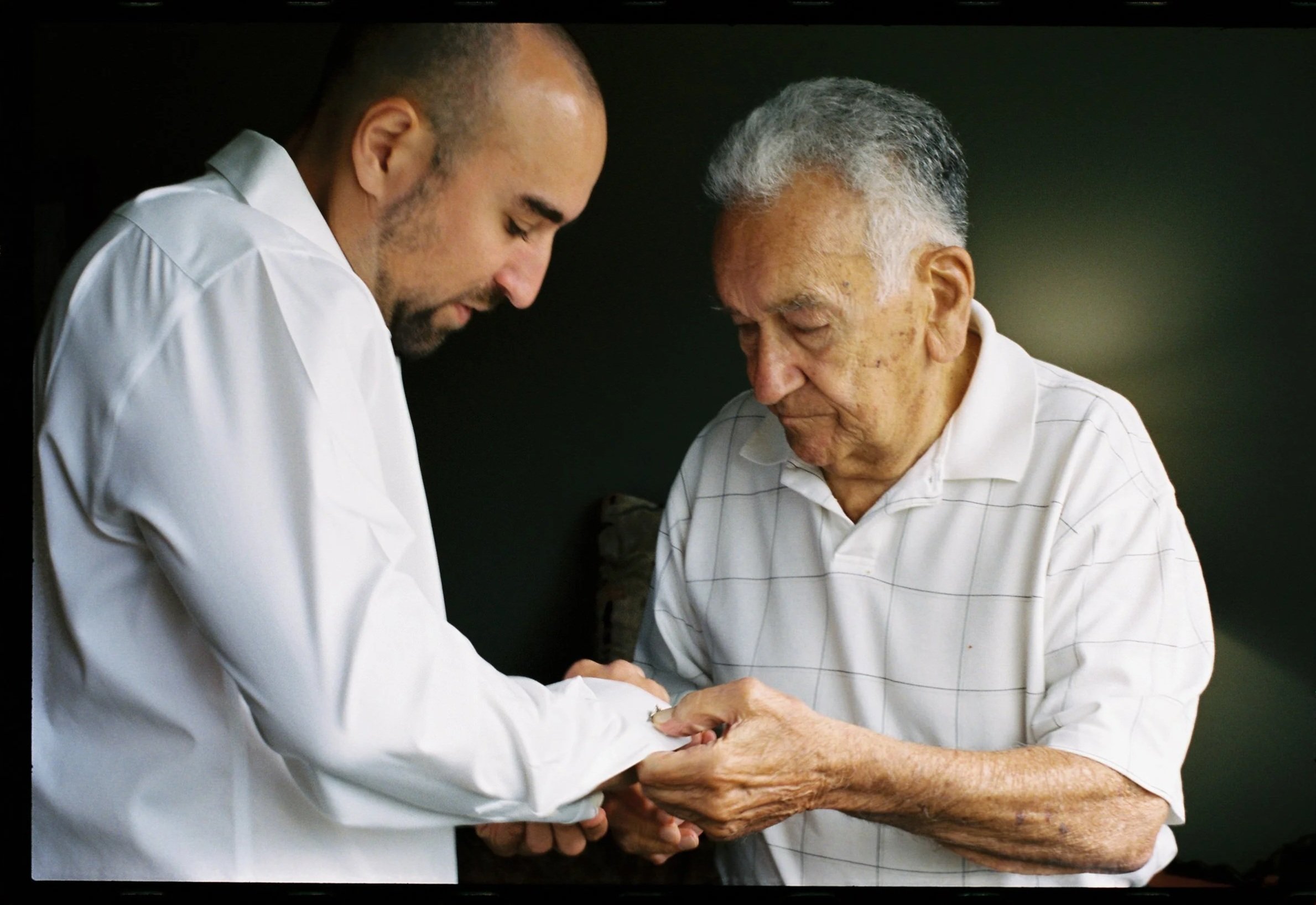Someone helping a person put on cufflinks