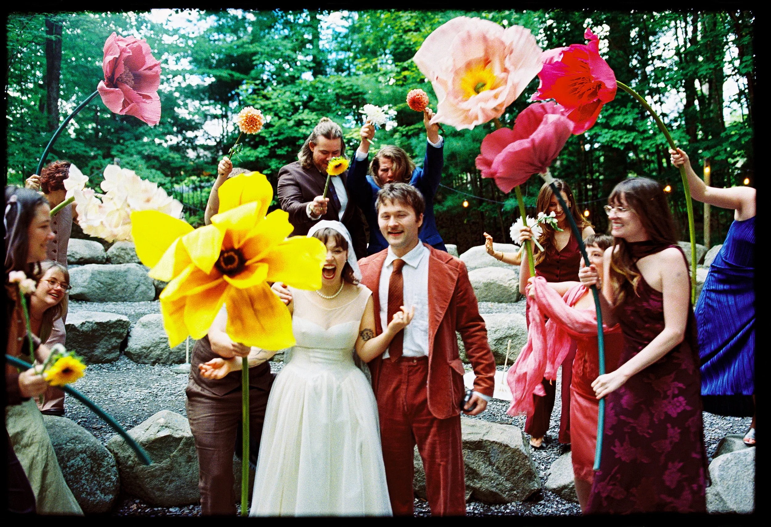 Newlyweds walking in between their guests who are holding large flowers around them