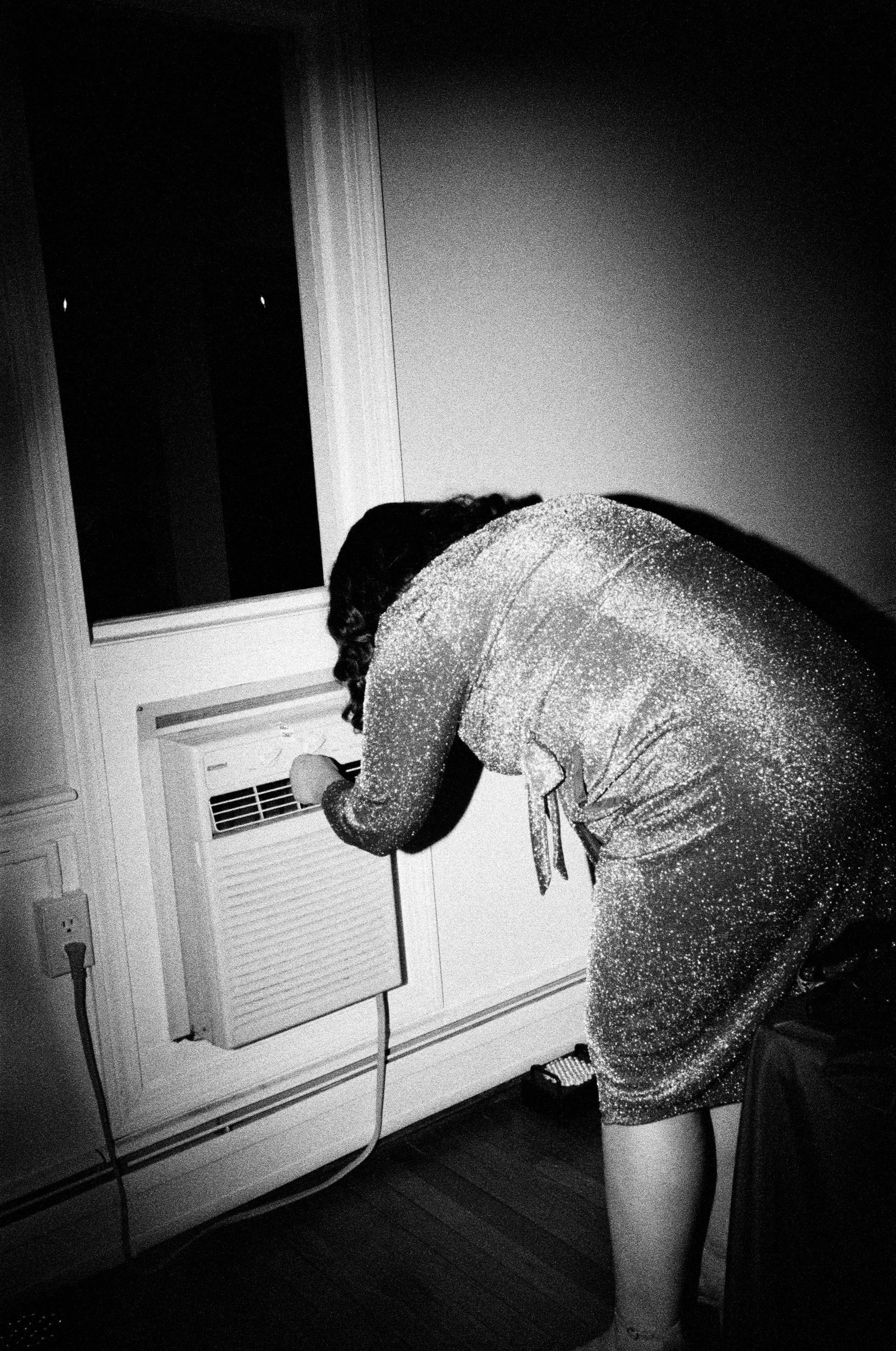 A person leaning over and turning on an air conditioner