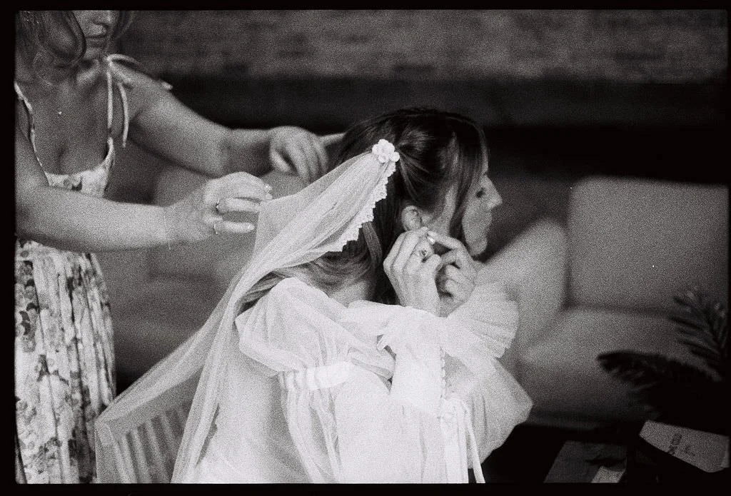 A person helping someone put on a veil before their wedding