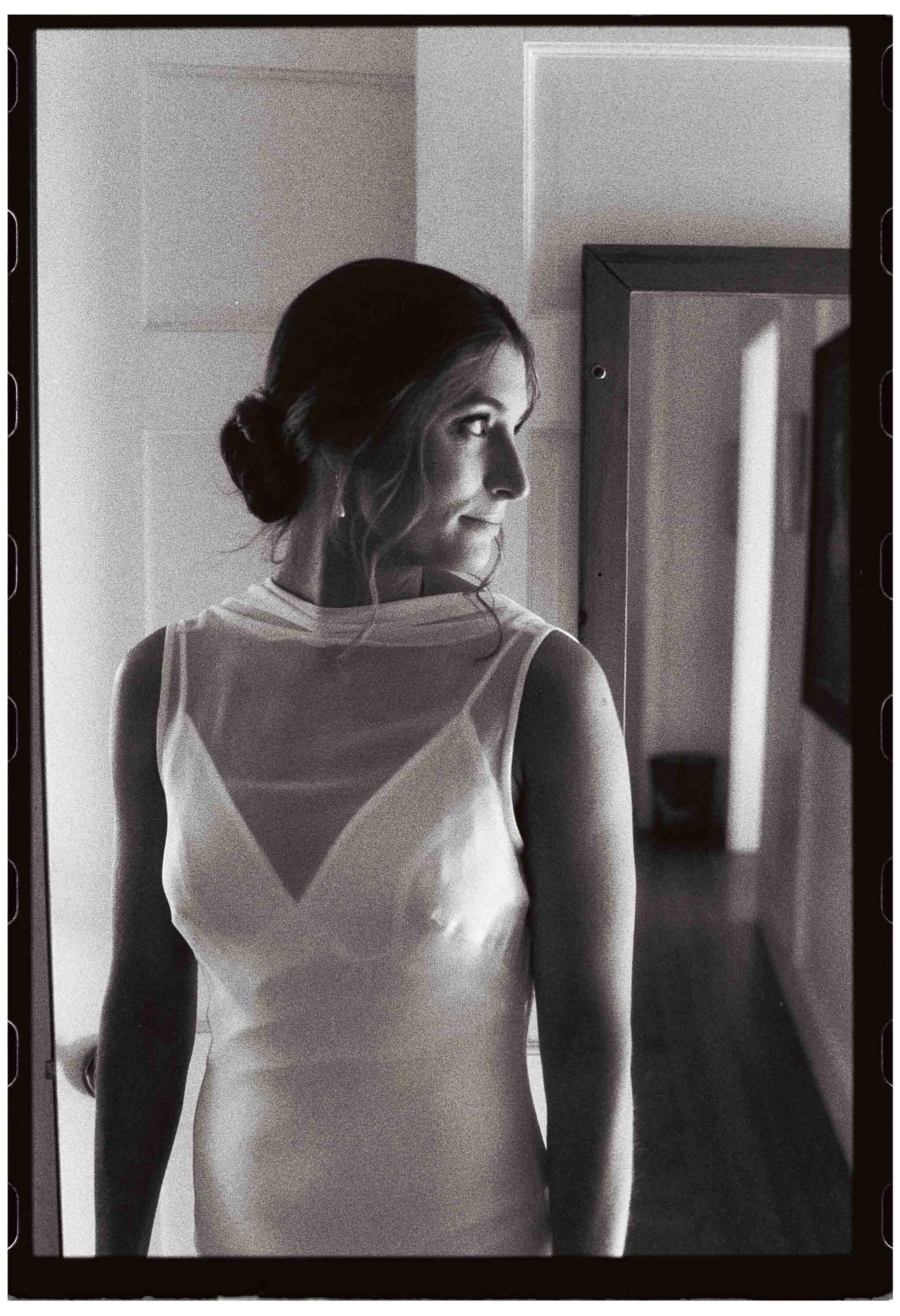 black and white film photo of bride looking over shoulder before first look