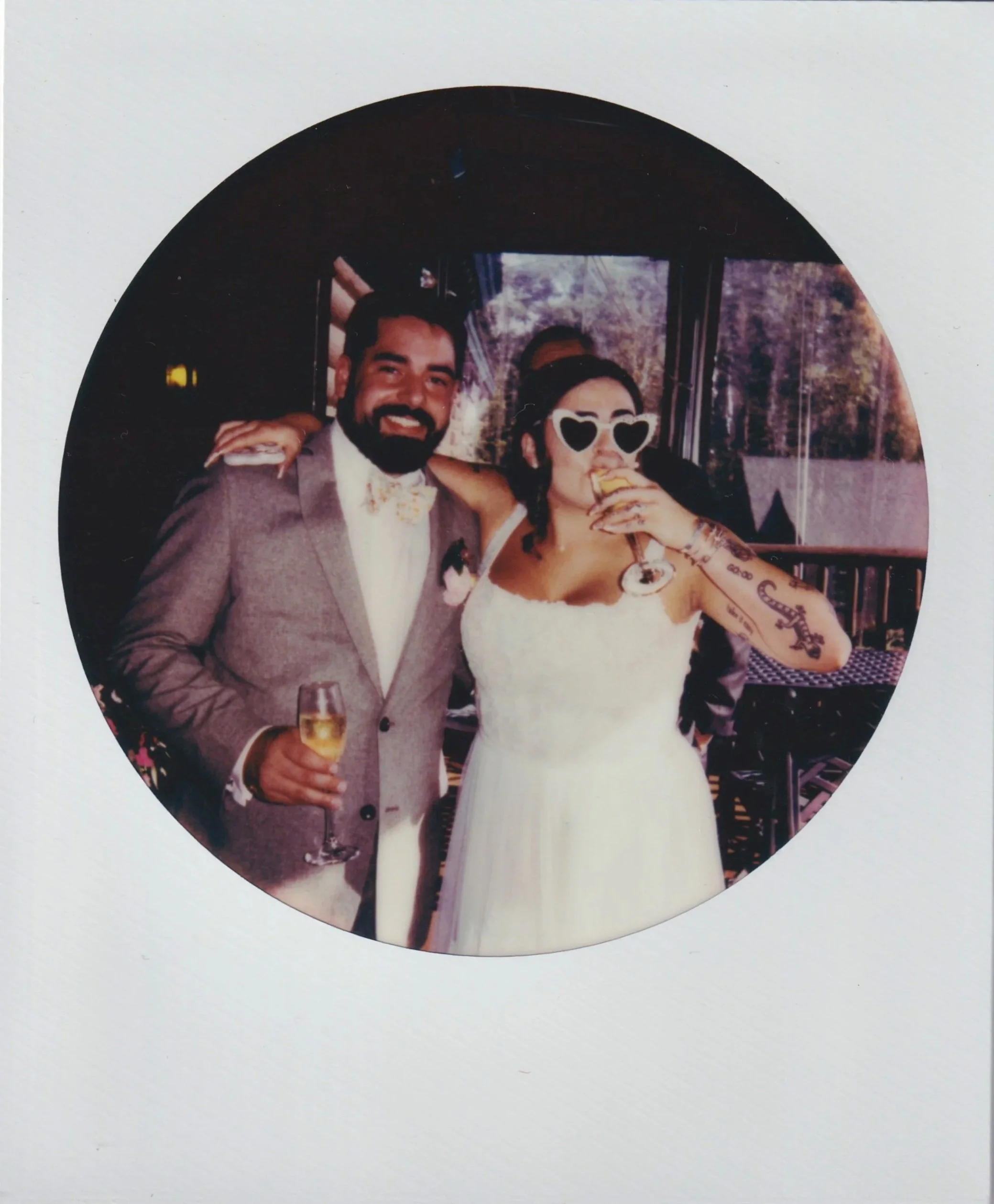 A newlywed smiling with their partner next to them drinking champagne