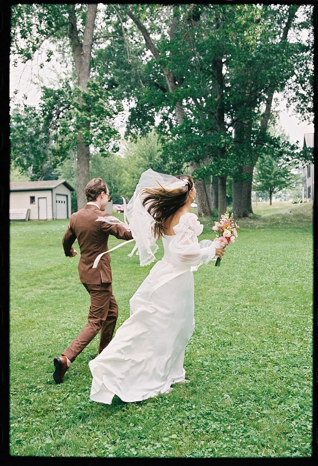 Newlyweds holding hands and running in a field