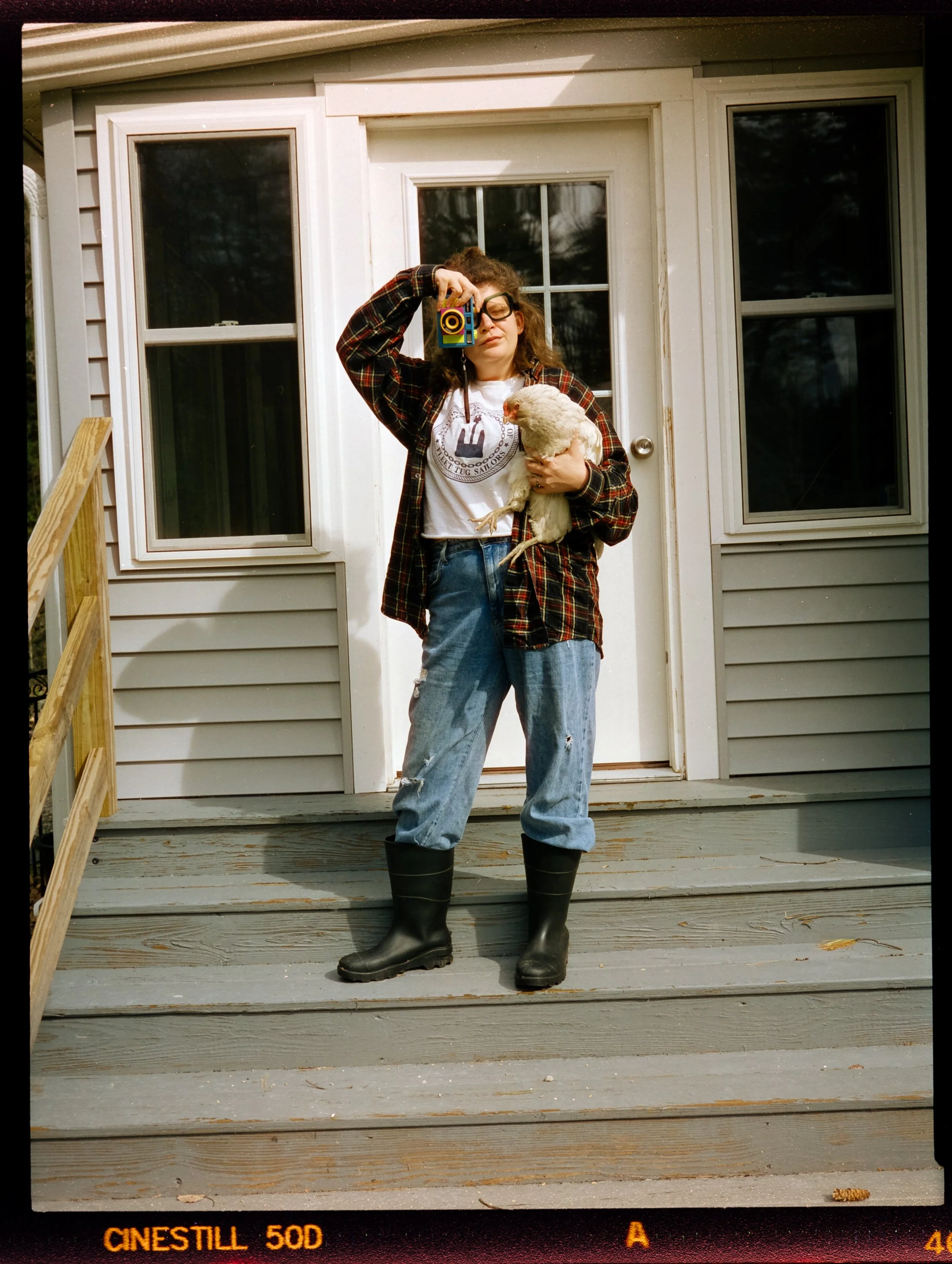 Mel taking a photo while holding a chicken in the other hand