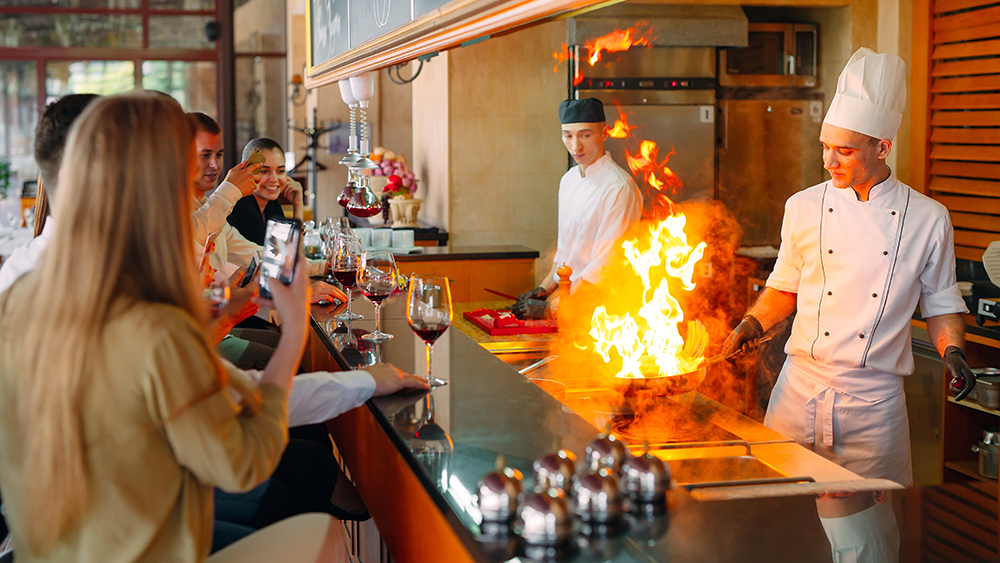 A chef prepares food in front of the visitors in the restaurant