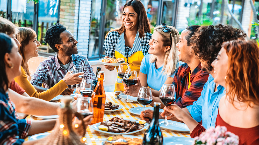 A bunch of friends laugh and smile while sitting at an outdoor restaurant