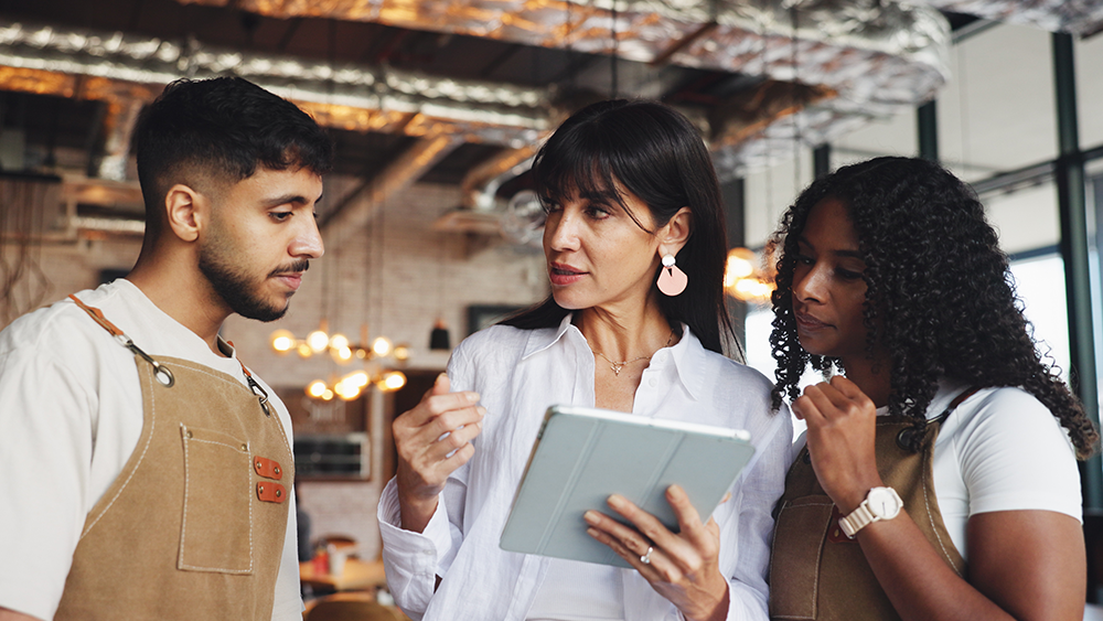 A restaurant manager going over an inventory plan with two young employees