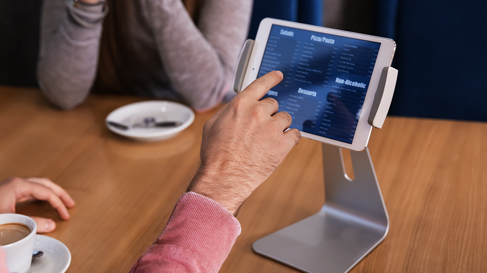 A restaurant guest ordering food at a tableside tablet menu