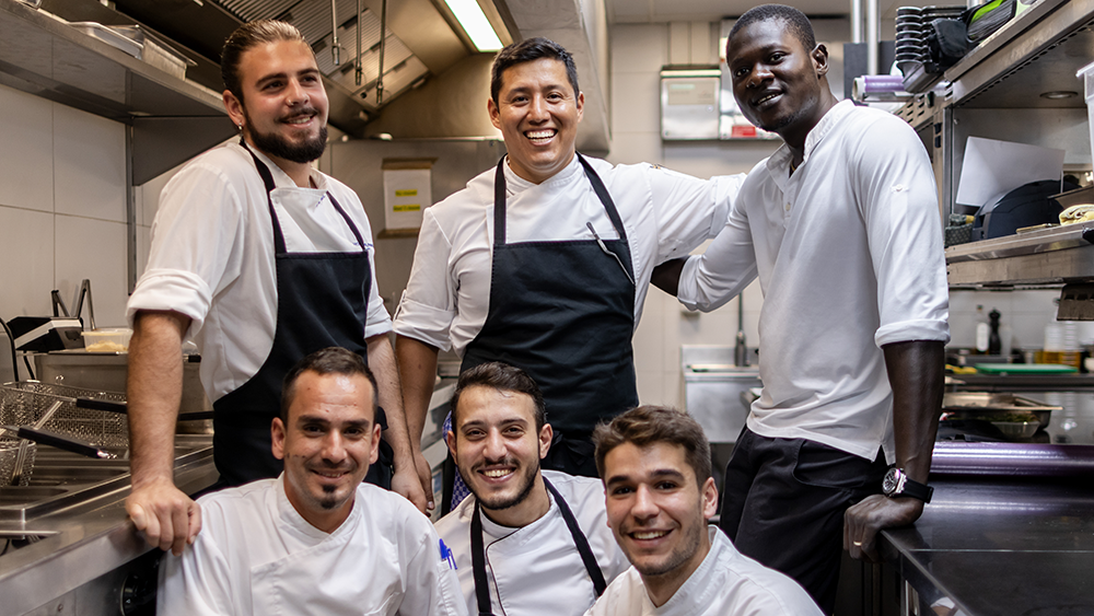 A group of restaurant chefs and a manager in a group photo smiling