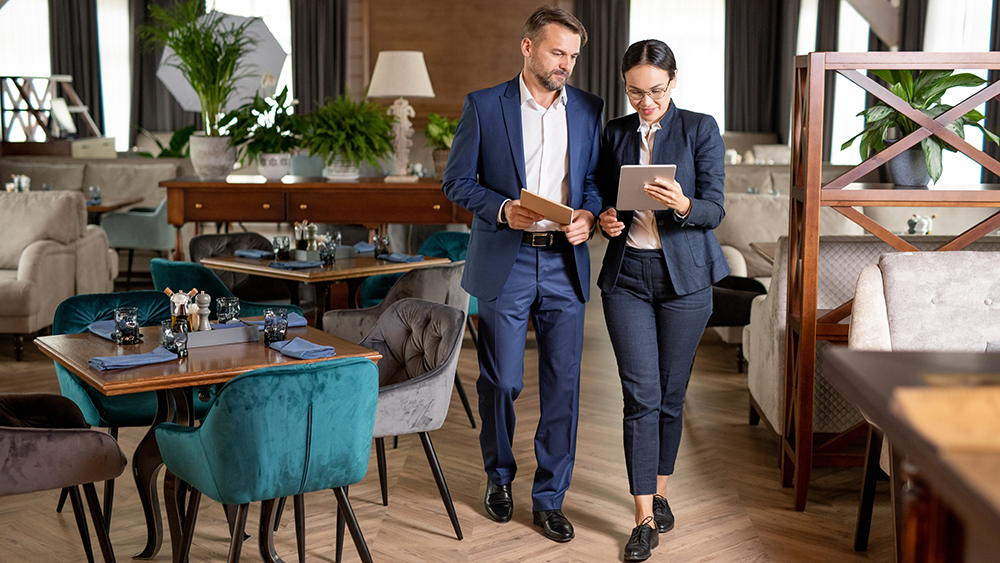 A restaurant owner and another small business owner chat while walking