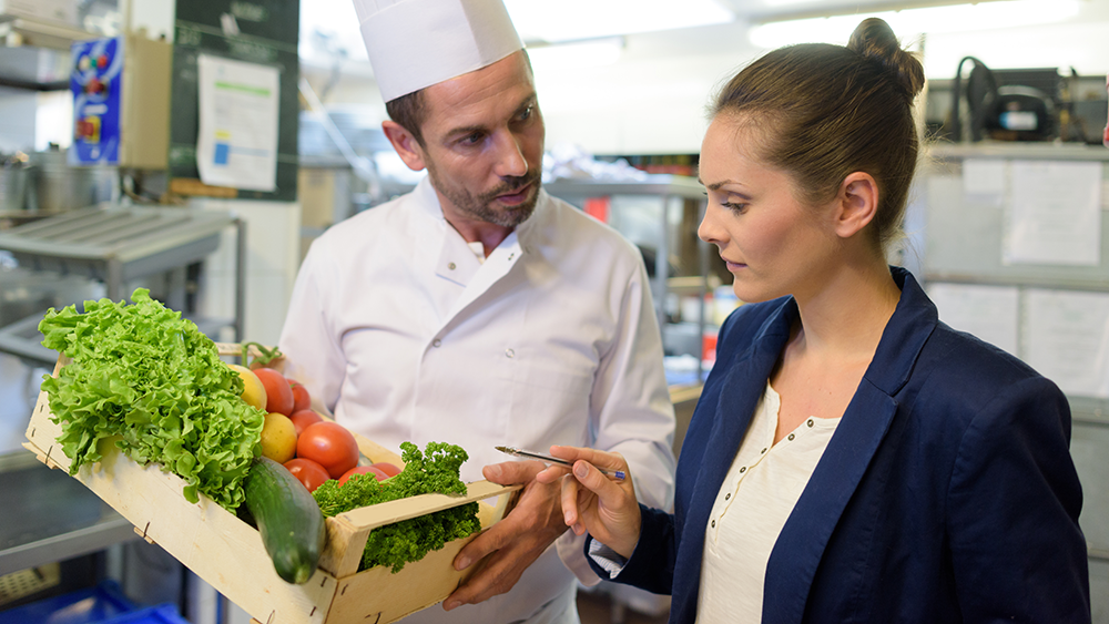 A restaurant chef and manager look over produce inventory