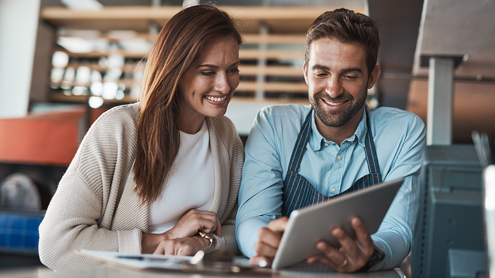 A restaurant owner and manager look over an ipad.