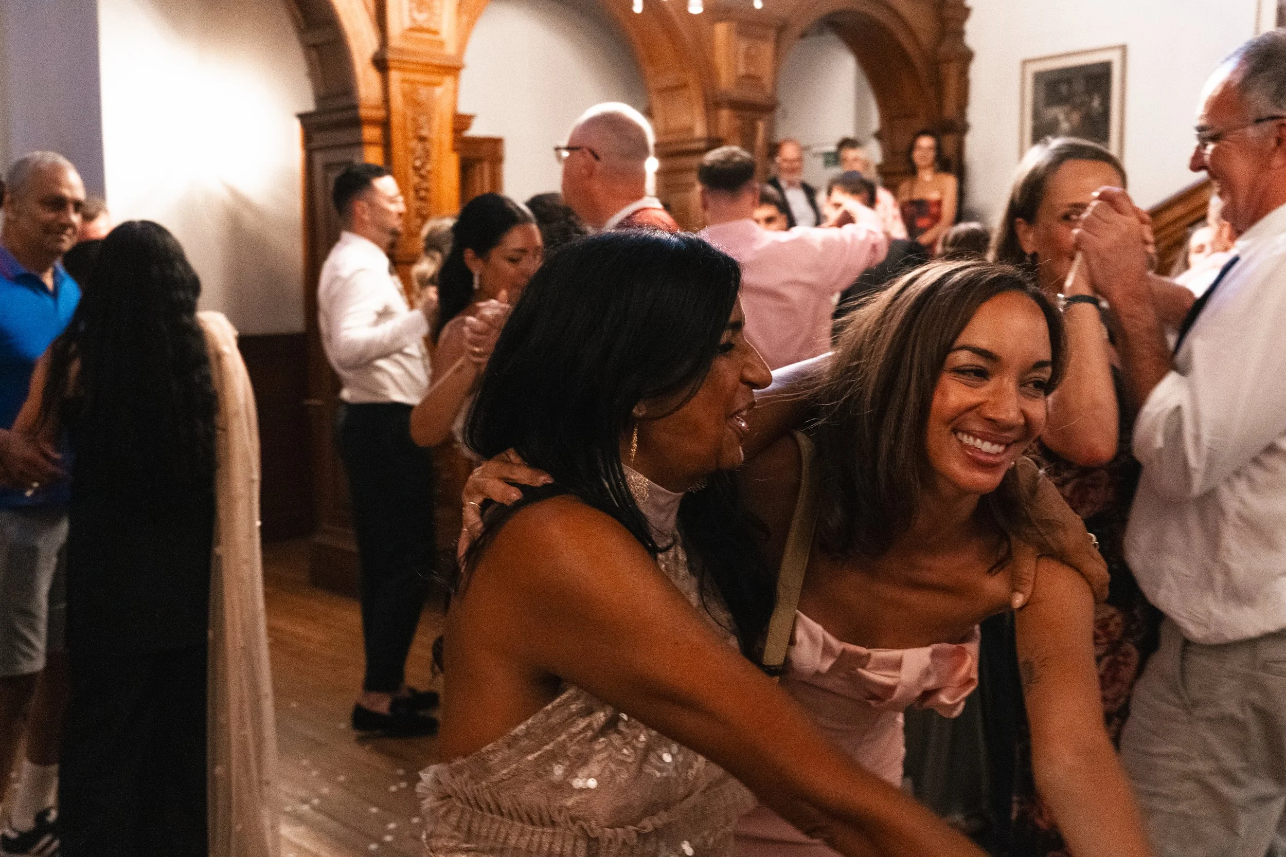 People dancing and socializing at an indoor party, with some smiling and enjoying the moment.