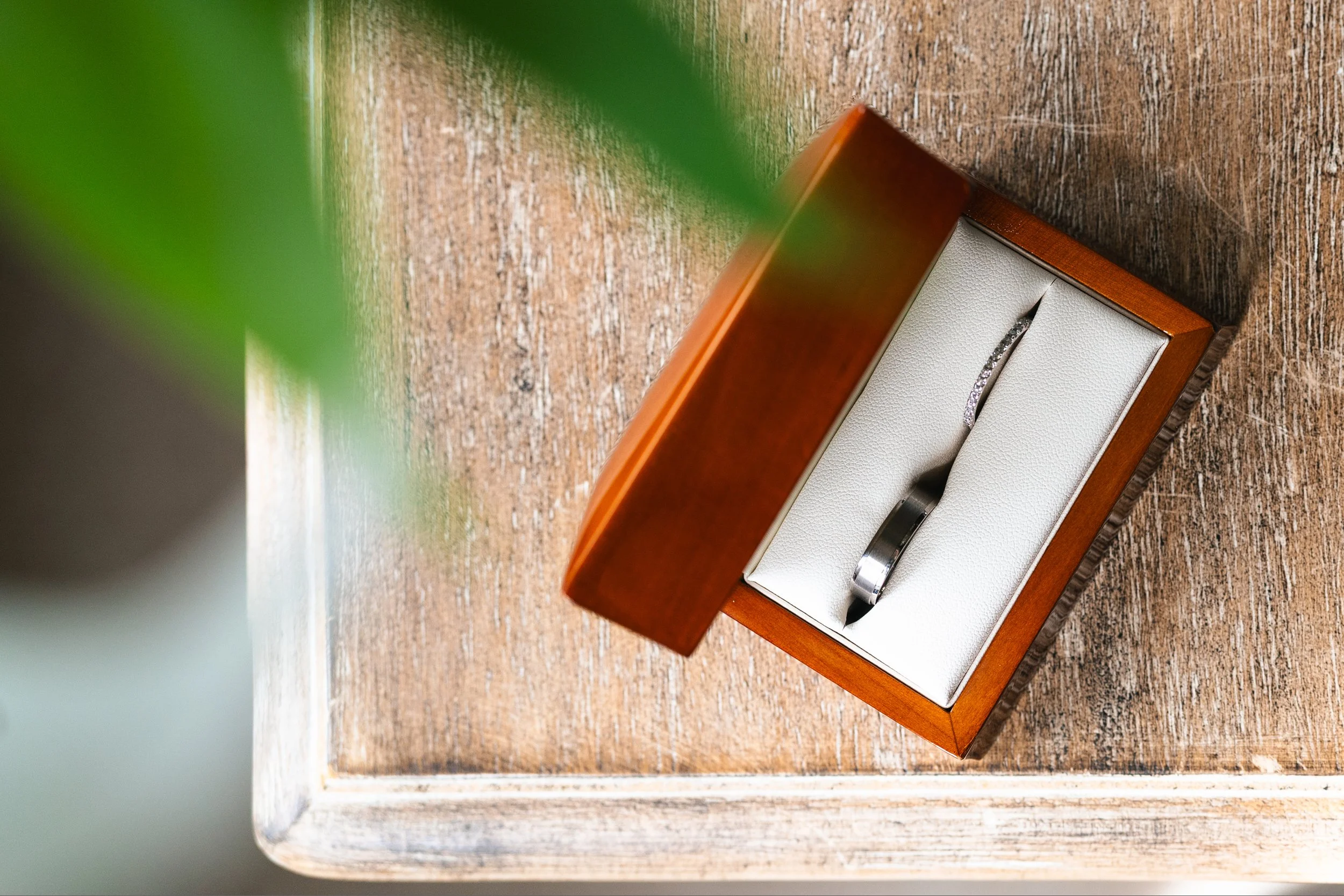 A ring with small diamonds in a wooden box on a wooden surface.