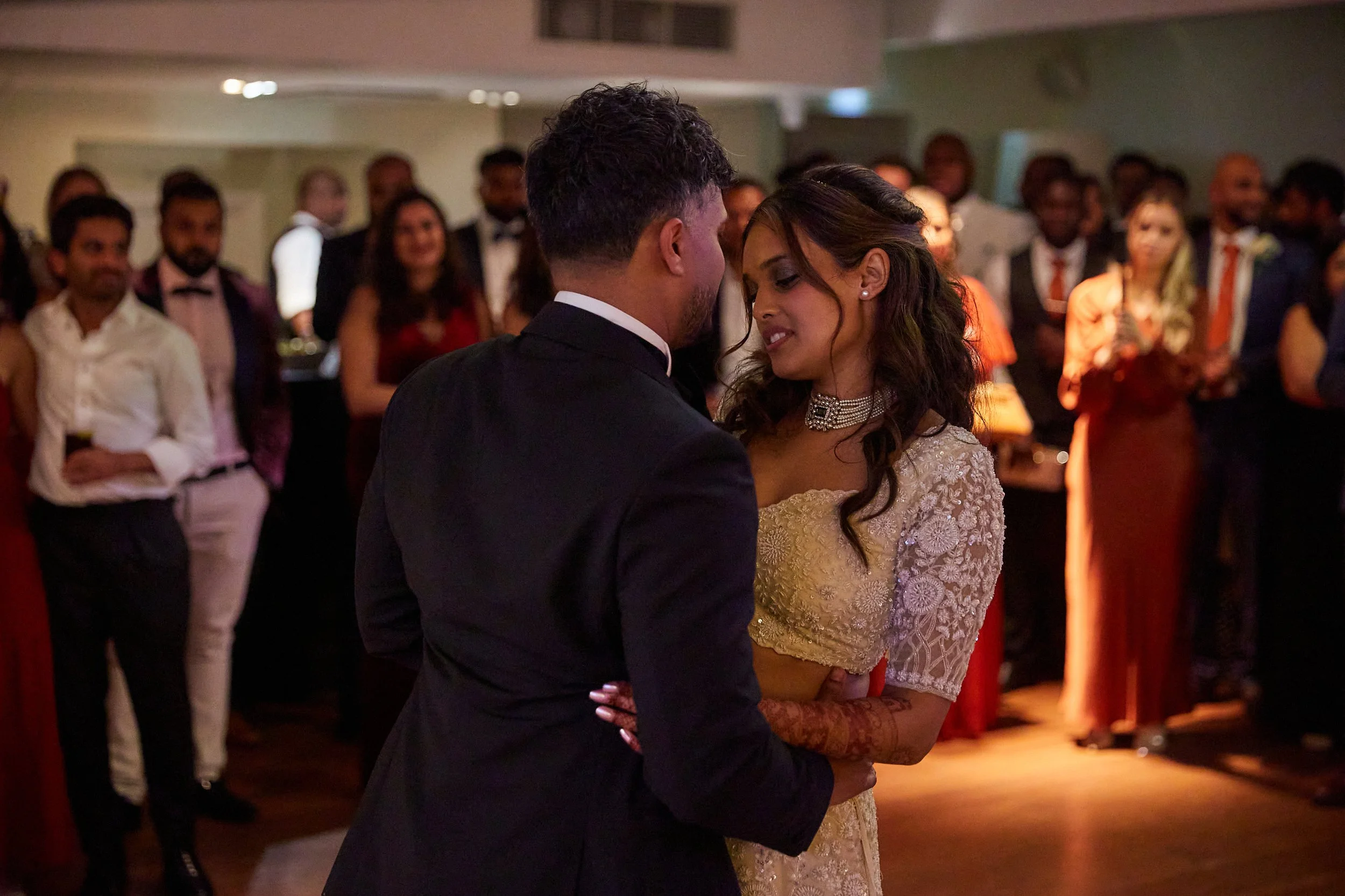 A couple having a romantic dance at a wedding reception with guests watching.