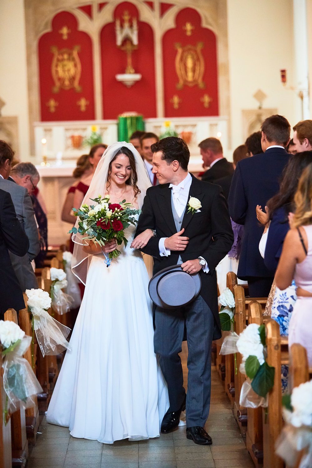Bride and groom walking down the aisle in a church after their wedding ceremony, surrounded by guests.