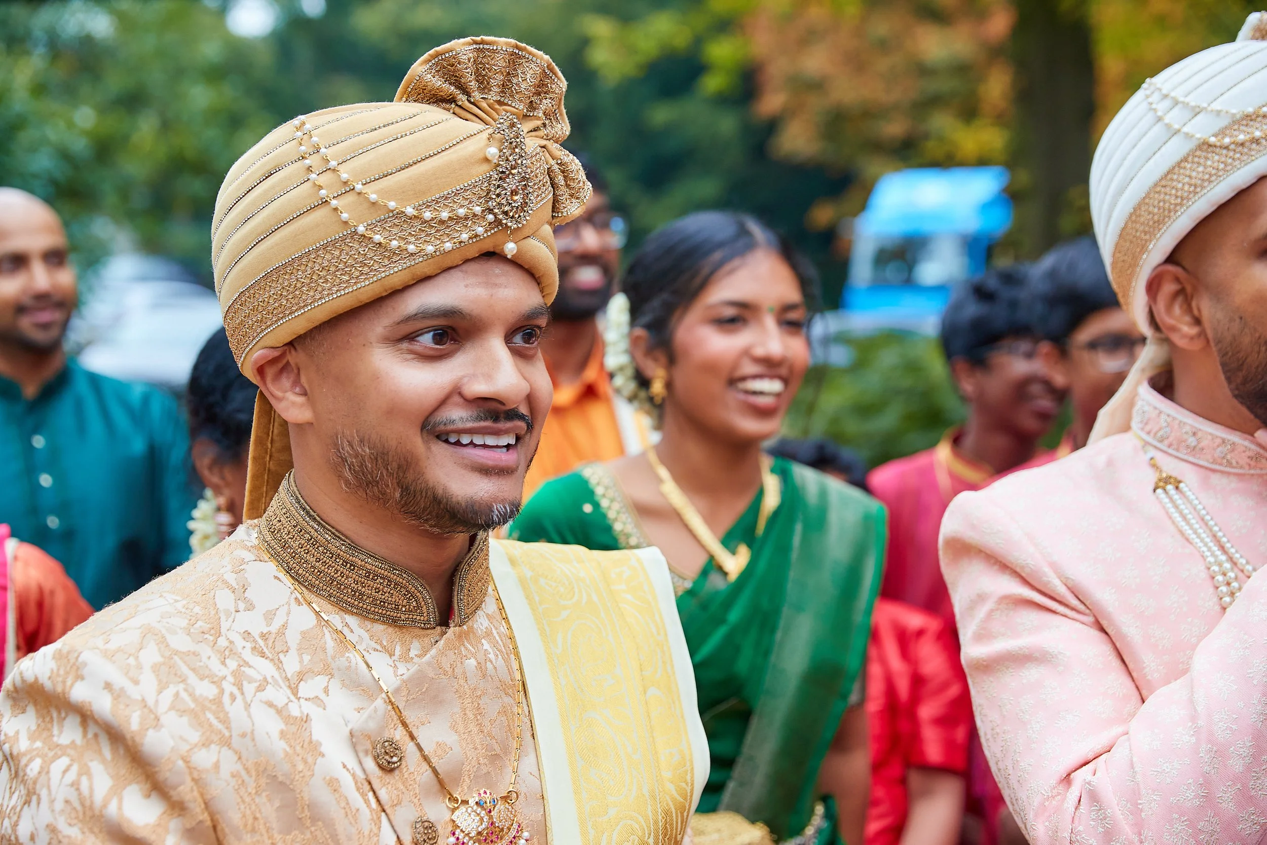 A group of people dressed in colorful traditional Indian attire, celebrating a festive event outdoors.