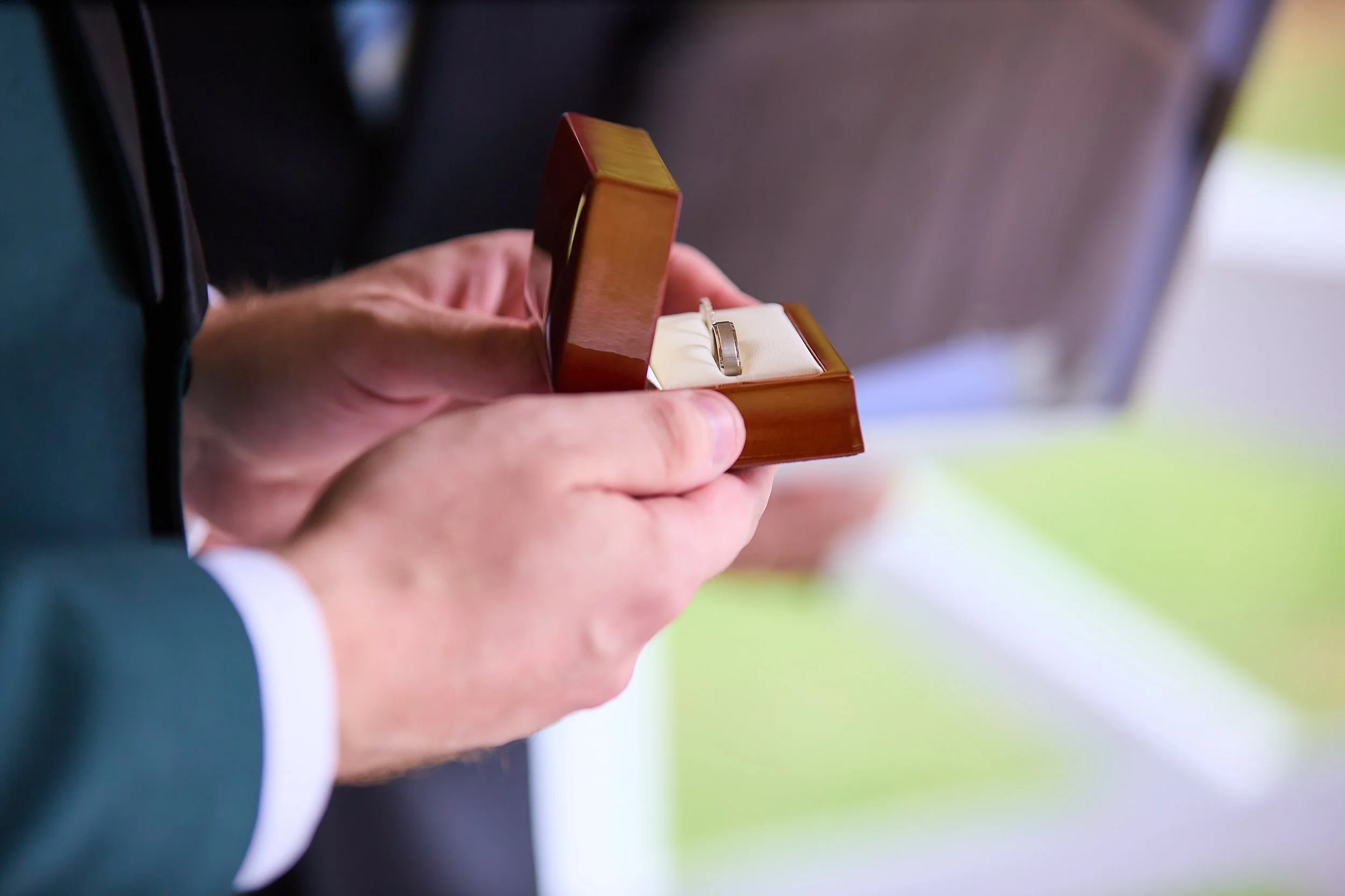 Person holding a wooden jewelry box with a ring inside.