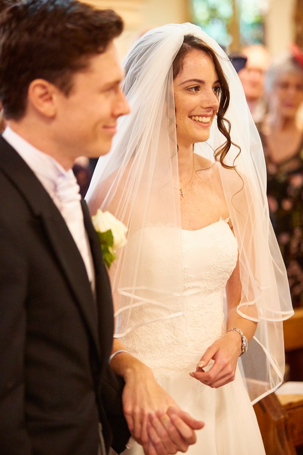 Bride and groom holding hands during their wedding ceremony inside a church.