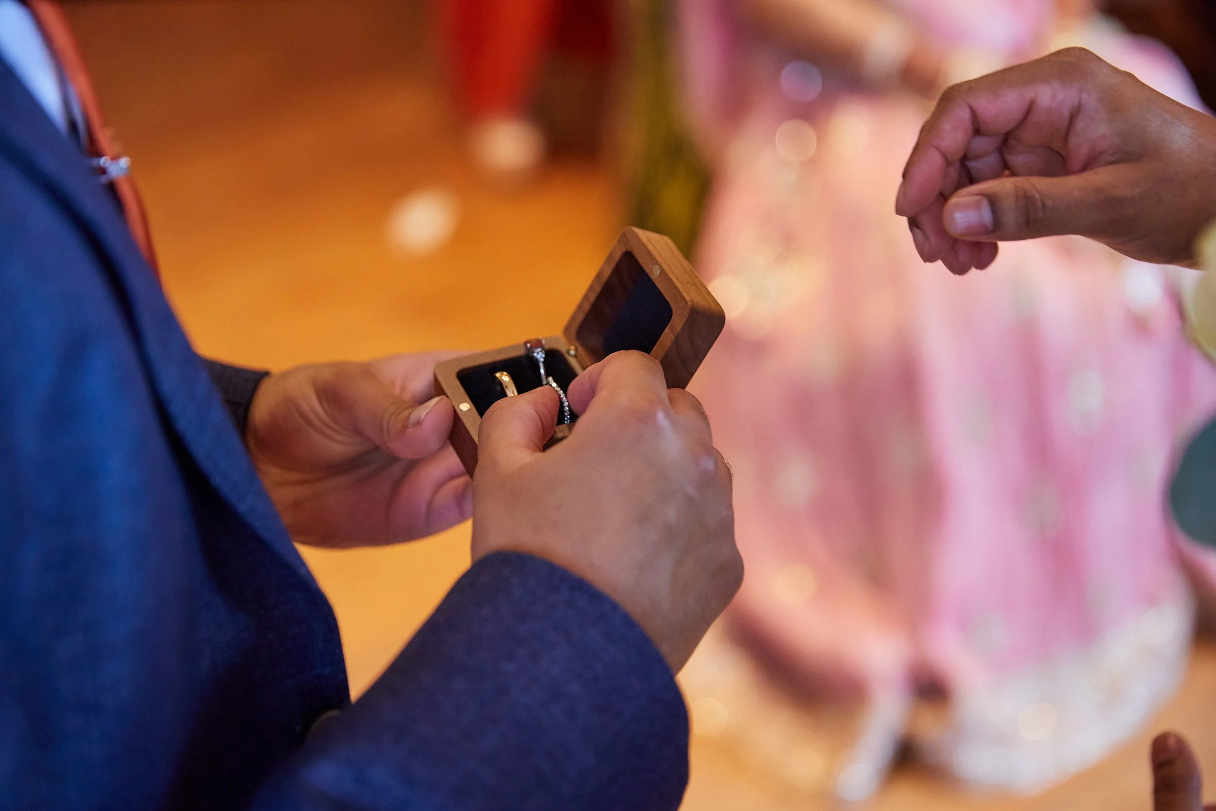 Person holding an open wooden jewelry box containing rings, during a gift exchange or special occasion.