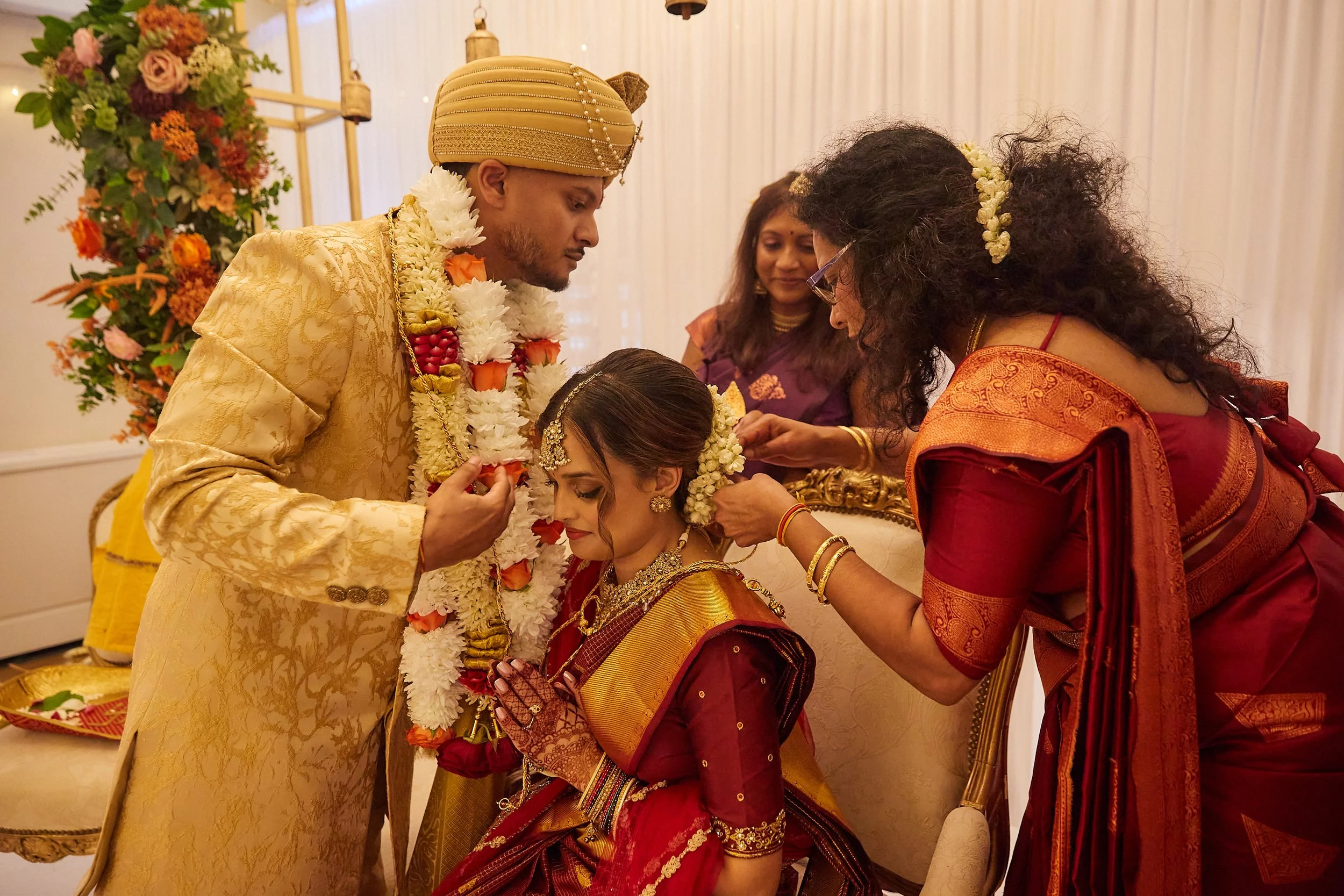 Indian wedding ceremony with bride and groom in traditional attire, surrounded by family members.