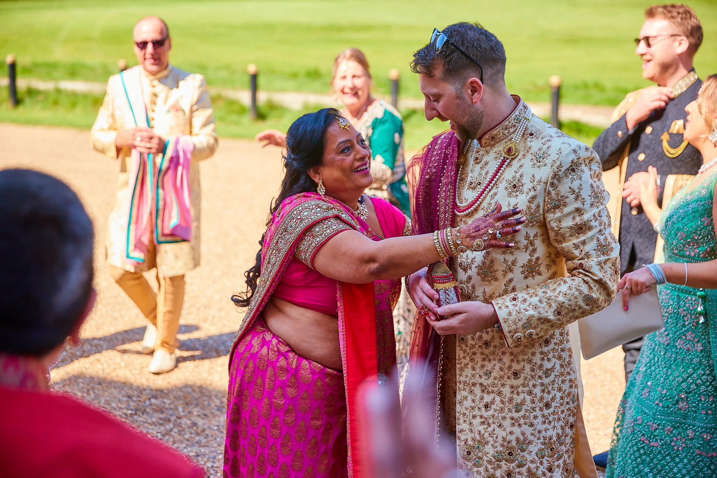 People celebrating at an outdoor Indian wedding, with the bride and groom in traditional attire and friends in colorful clothes.
