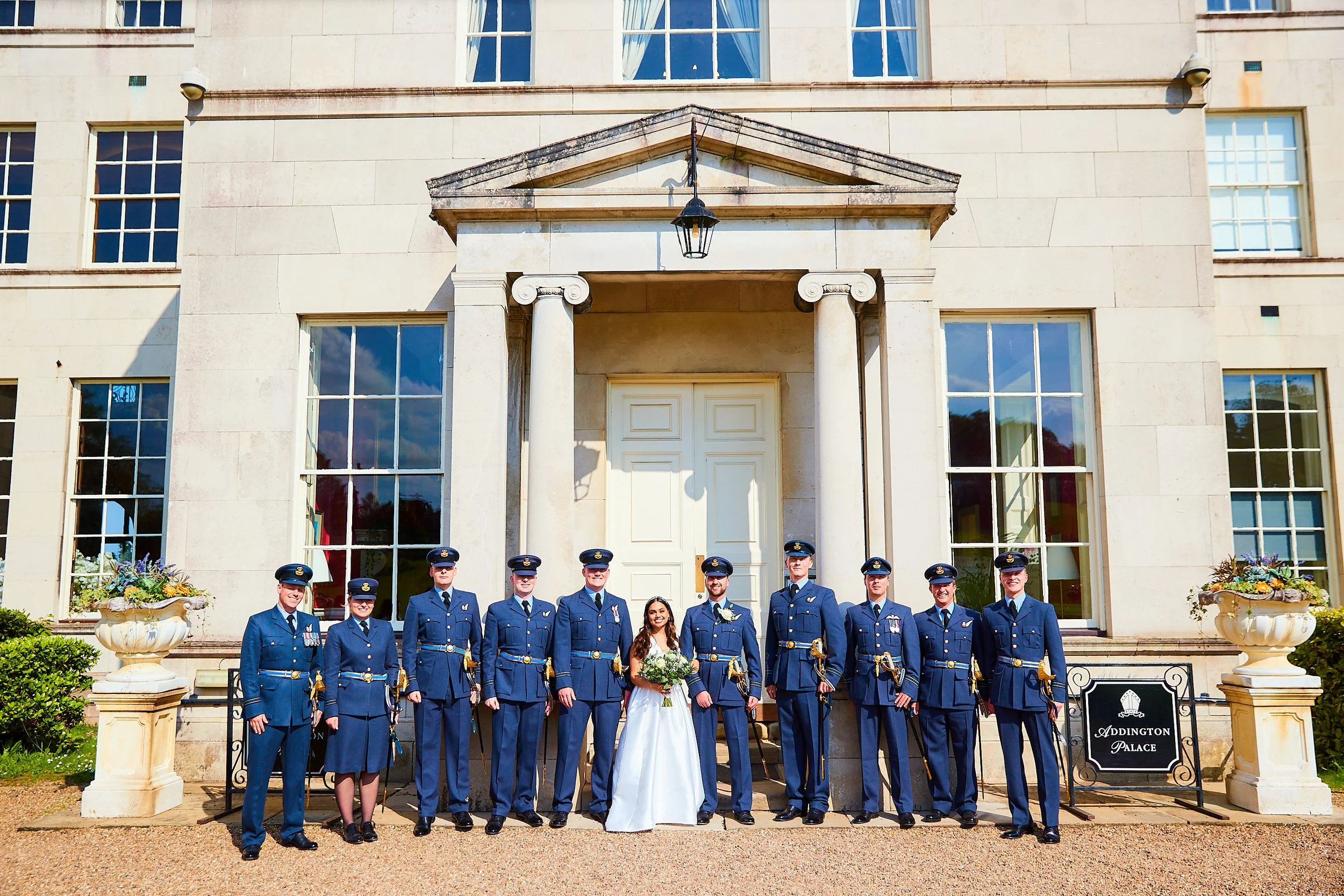 Group of military personnel in uniform posing for photo in front of a large building with columns and a sign reading 'Addington Palace'