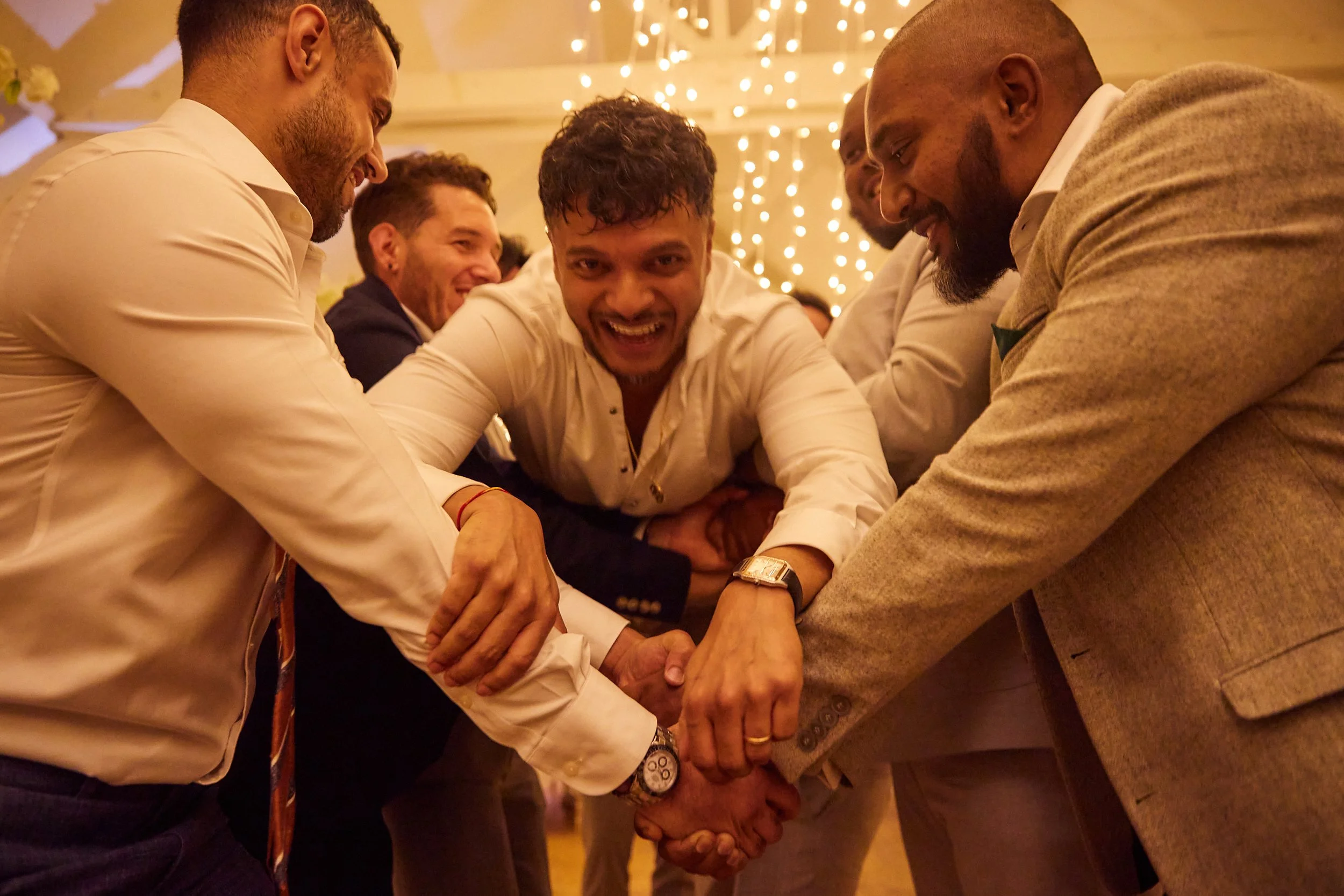 A group of men in formal attire participating in a team-building activity at a celebration or event, showing enthusiasm and camaraderie.