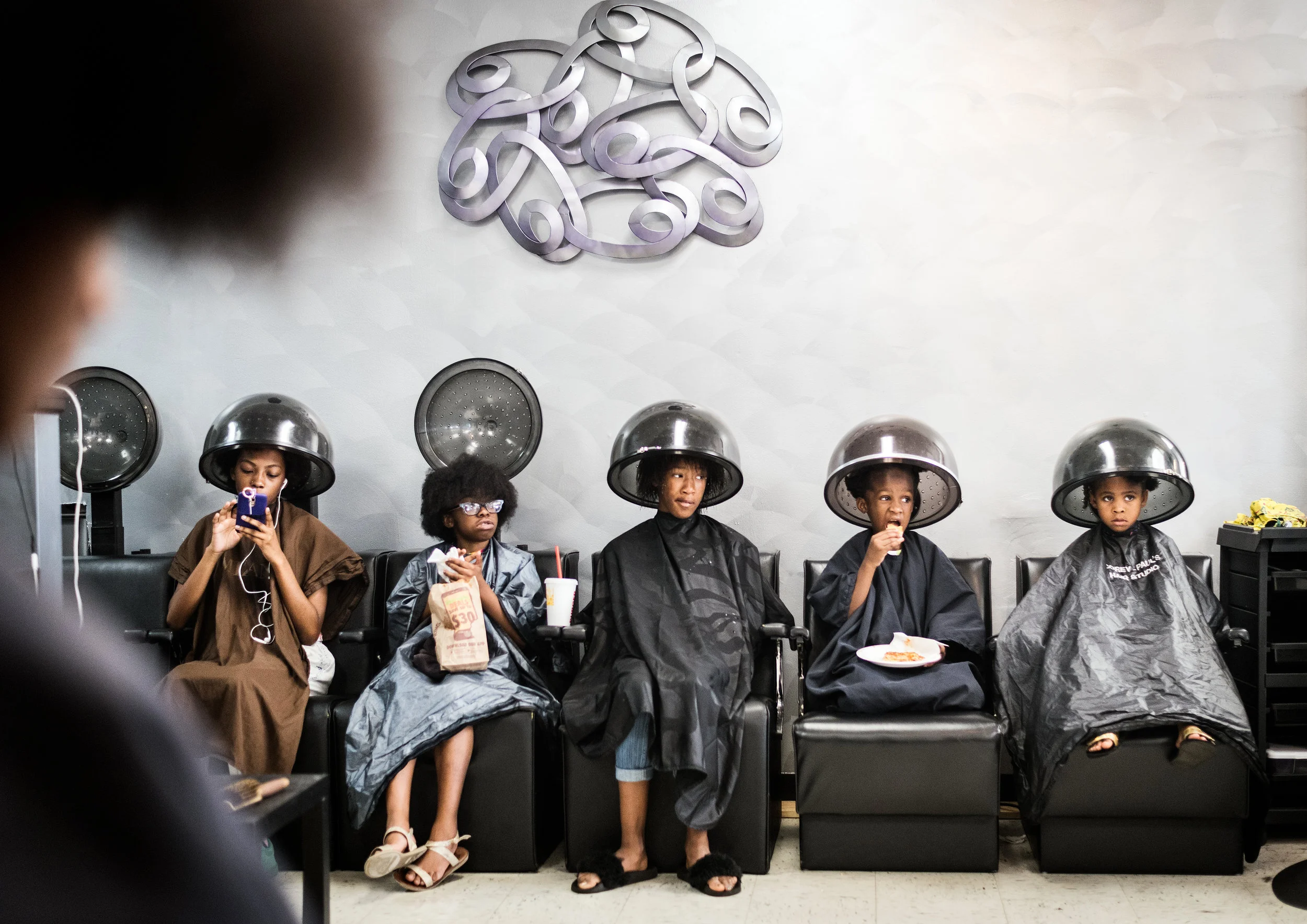  Janae Washington (from left), 15, Chloe Clement, 8, Tylashia Mack, 11, Talajah Hardy, 7, and Jamayla Kimbrough, 6, sit under the hair dryers while Nala Rose (foreground), 13, has her hair straightened by Paula Oloughlin during the fourth annual Grea