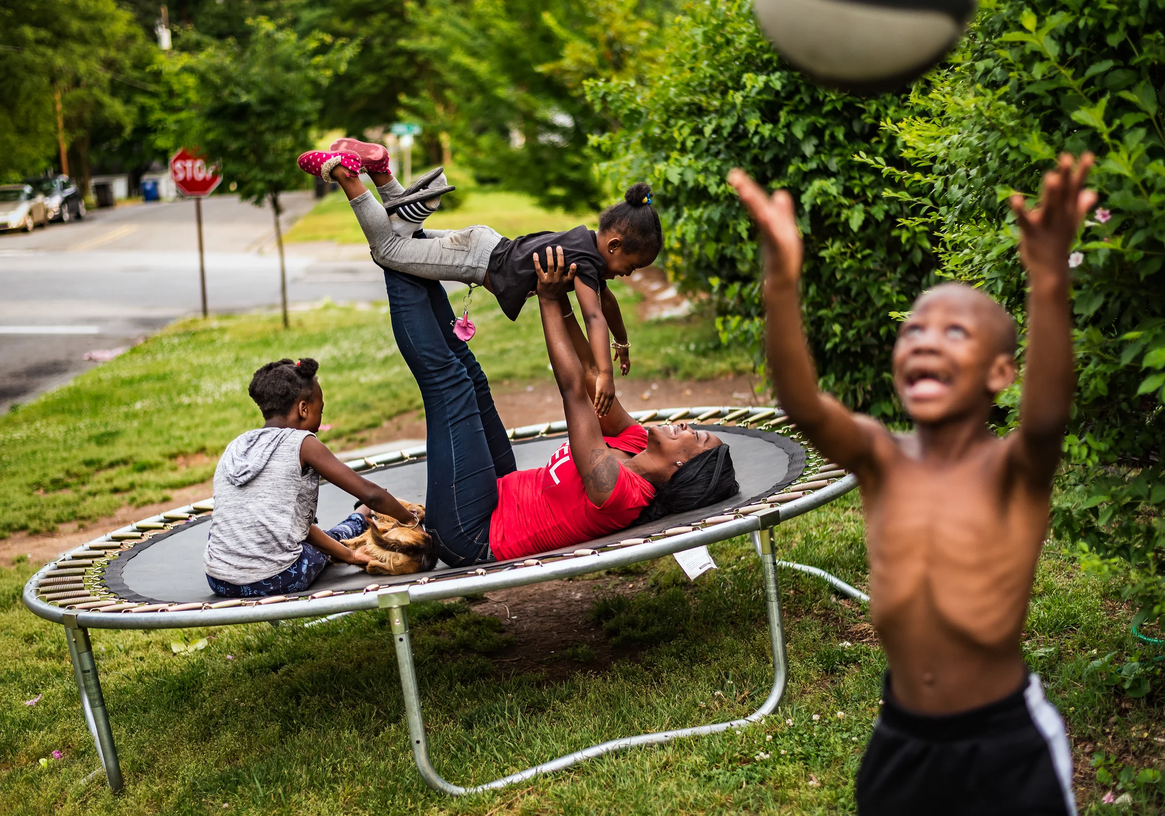  Jy'Quez McCoy (from right), 6, tosses a basketball while Ava Coleman holds Chelsea Coleman, 3, up in the air and Don'Nasia McCoy, 7, plays with their dog Maria on the trampoline in their front yard Thursday, May 17, 2018, in a neighborhood off of 27