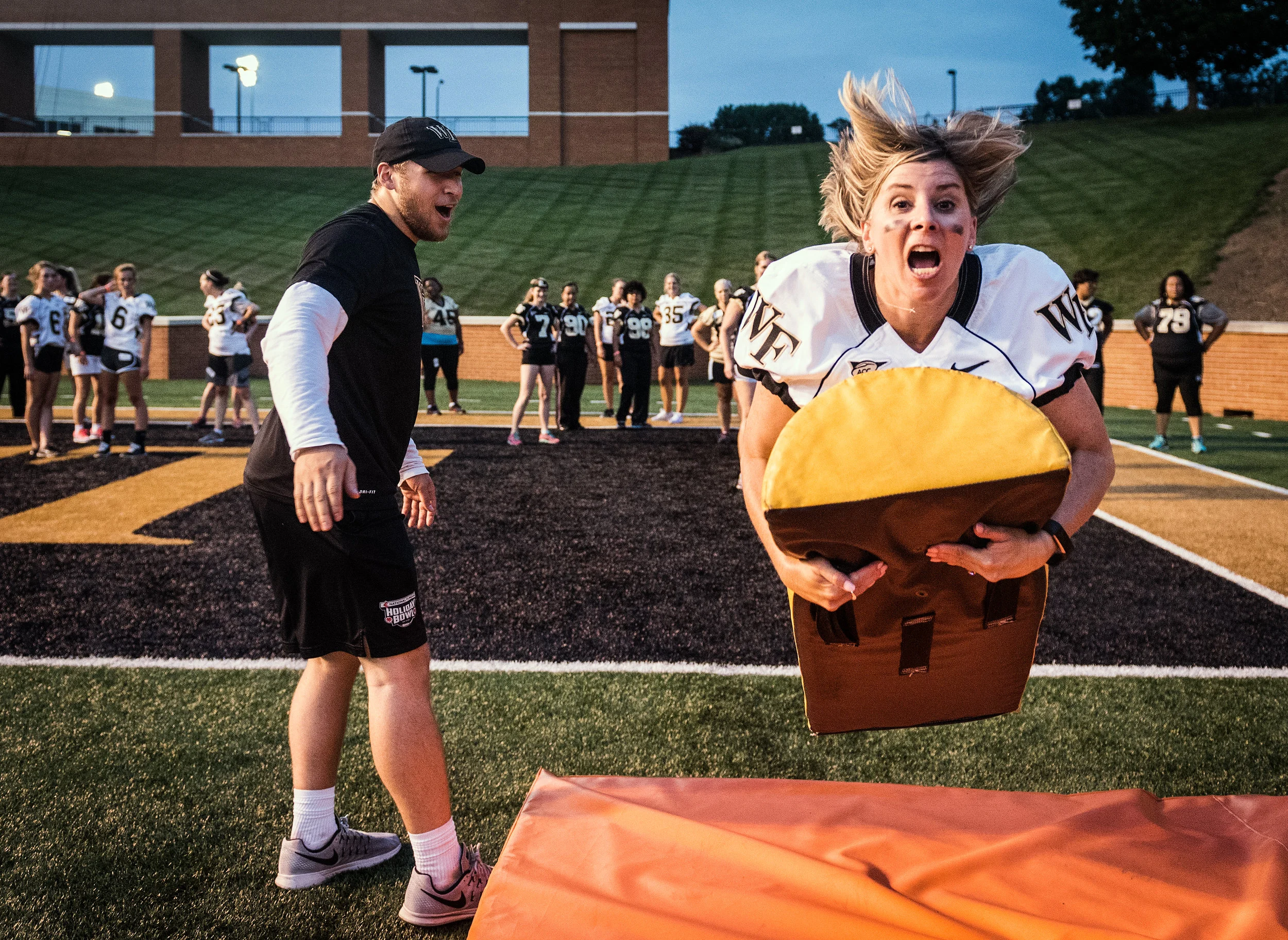  Jen Ruggiero, wife of offensive coordinator and quarterback coach Warren Ruggiero, tackles a half round football dummy during the 20th annual Wake Forest Women's Football Camp on Thursday, July 20, 2017, at BB&T Field in Winston-Salem, N.C. 