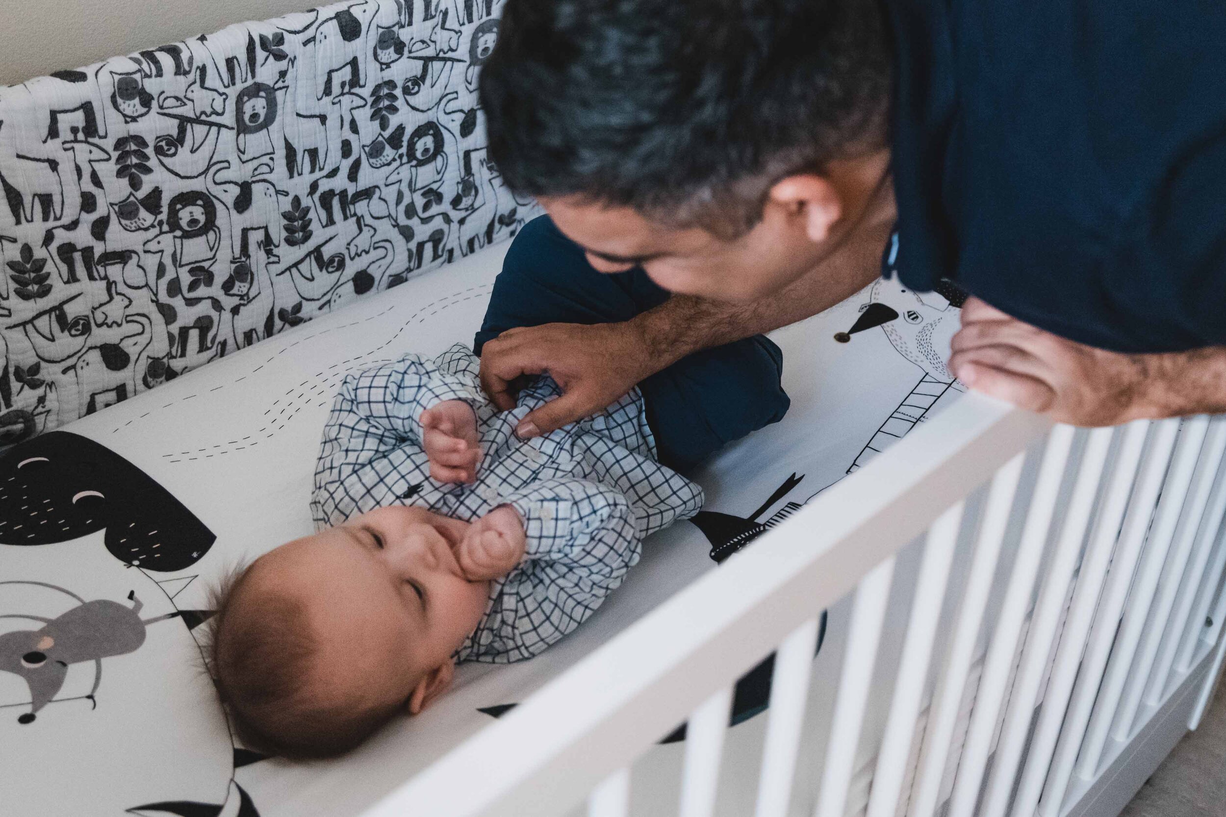 Dad with baby in crib at home