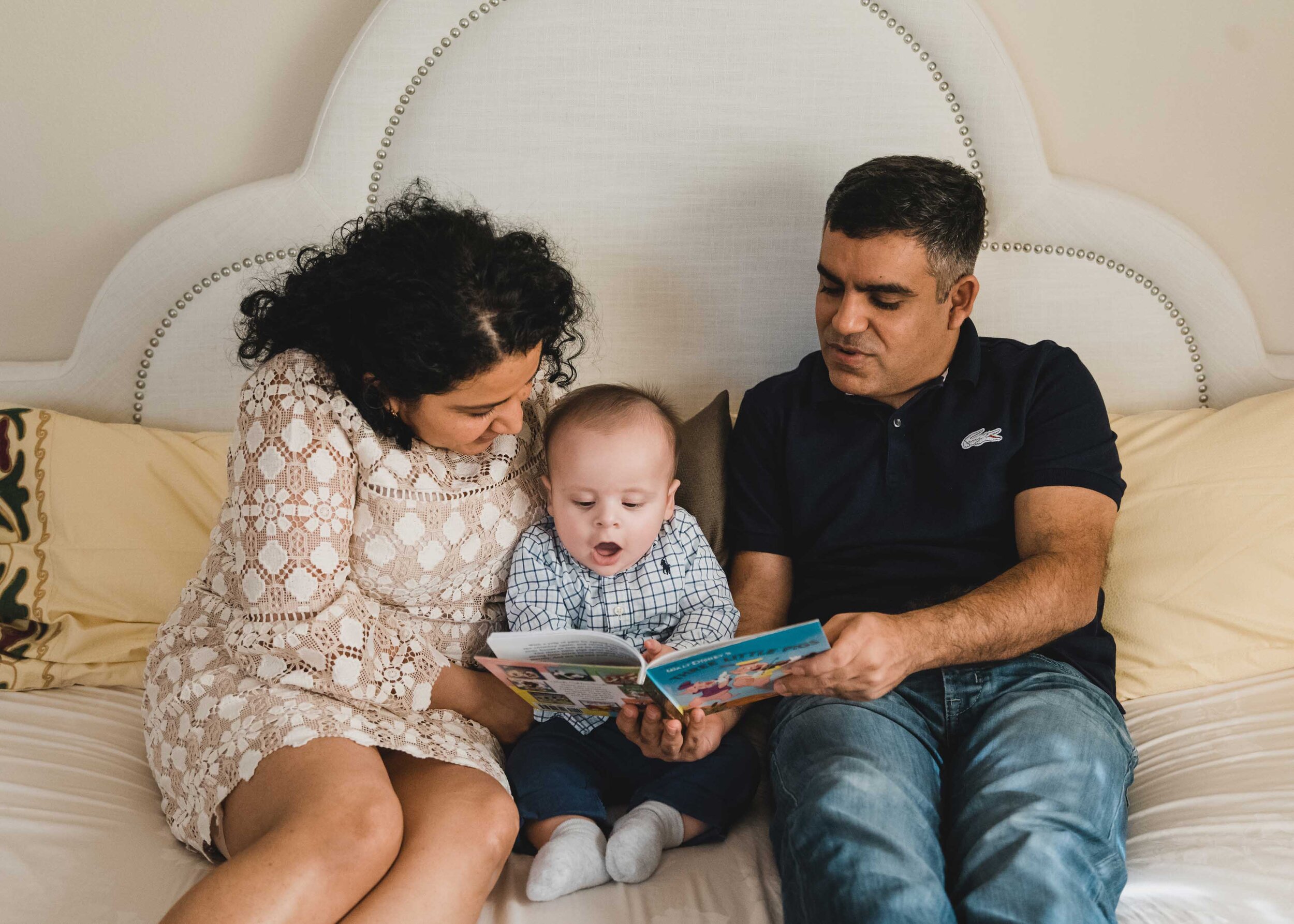 Mom, dad, baby reading together in bed