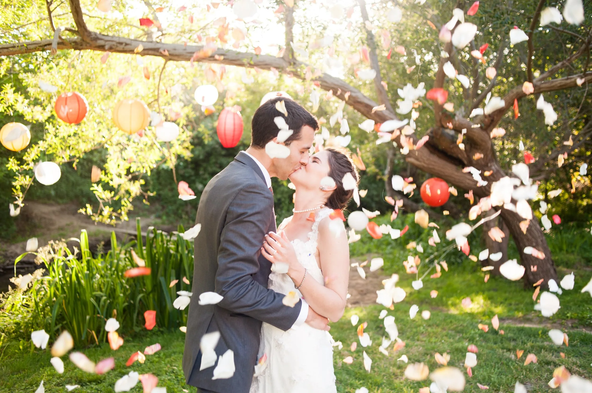 Bride and Groom Kiss underneath shower of flower petals