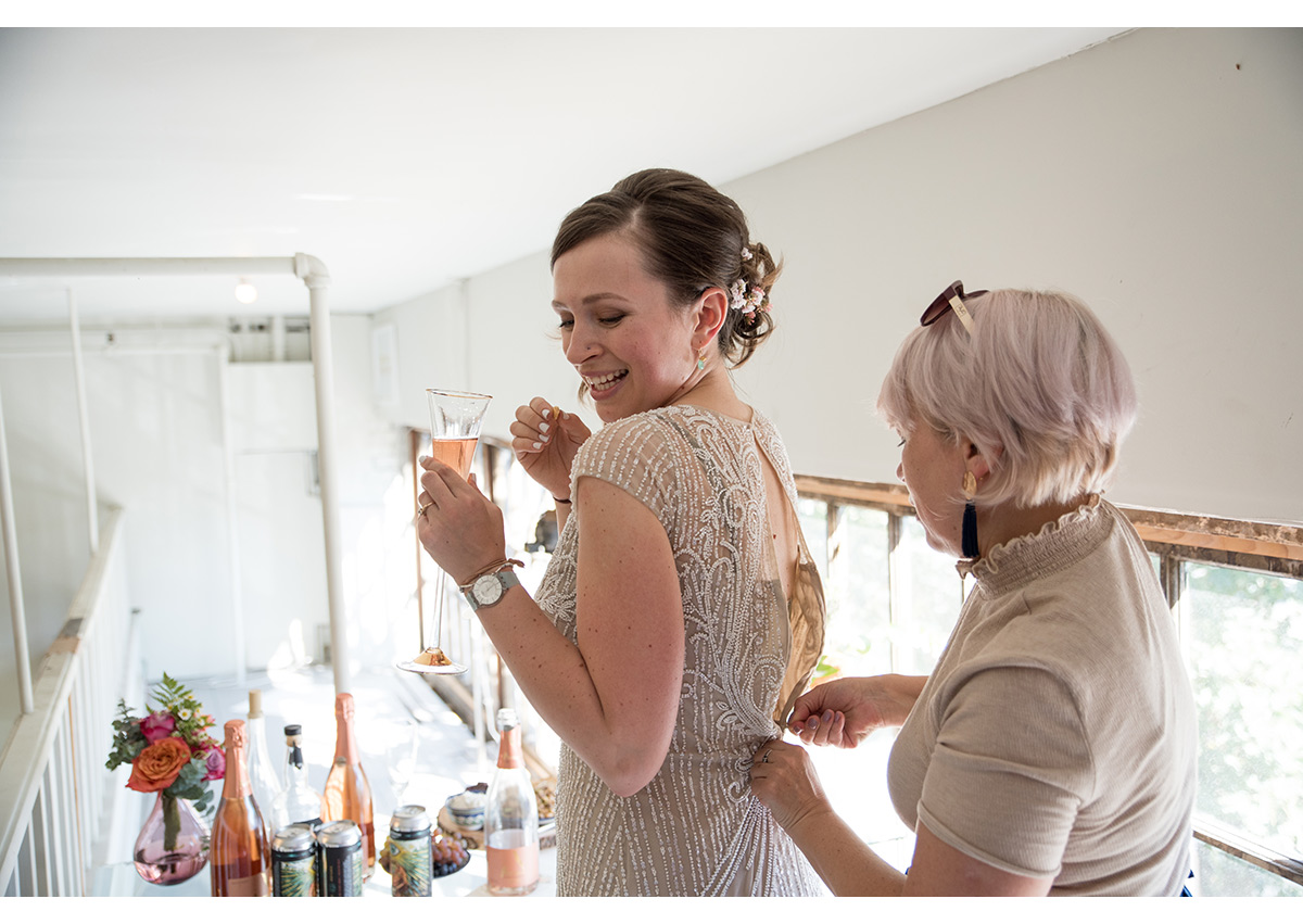 Mother helping daughter get into wedding dress