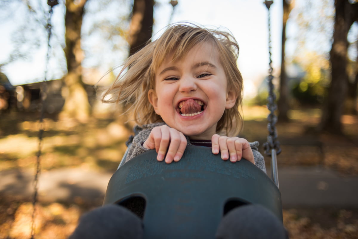 Candid of kid in swing being goofy