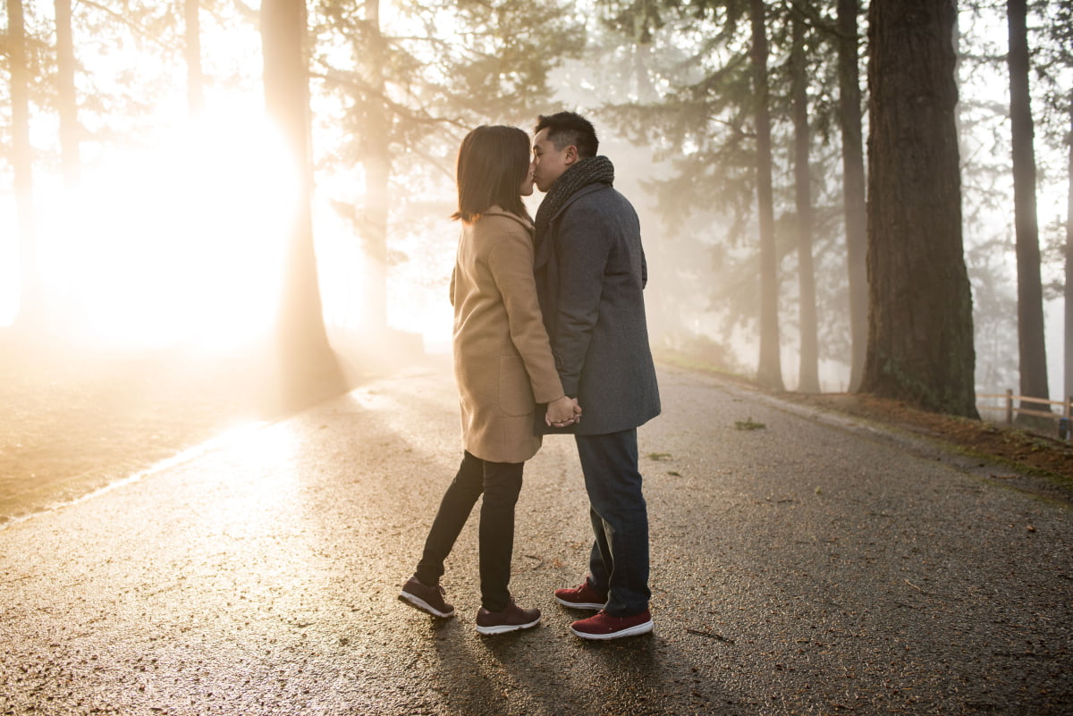 Couple kissing in dramatic sunlight and fog at Mt Tabor