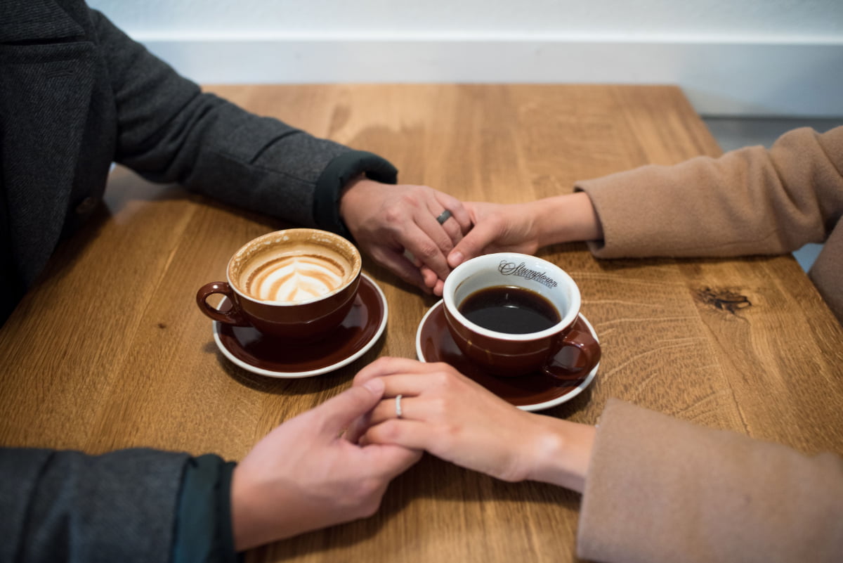 Detail photo of couple holding hands with coffee cups