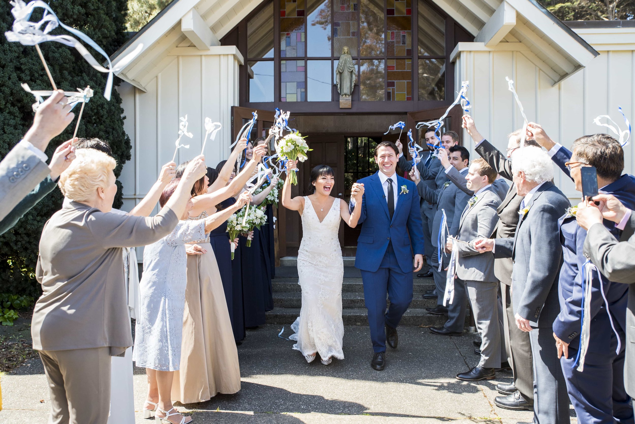 Bride and Groom exiting historic church as guests wave streamers