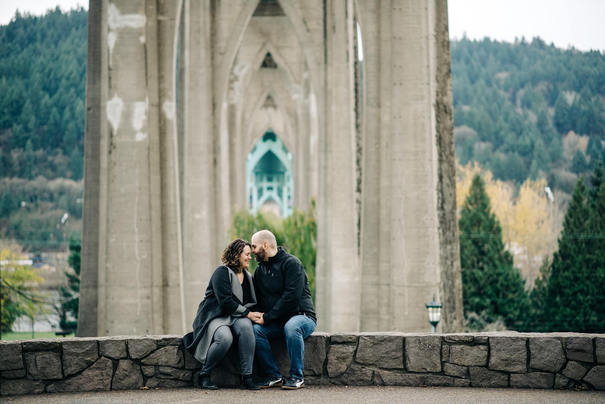 Couple sitting on wall under St. Johns Bridge