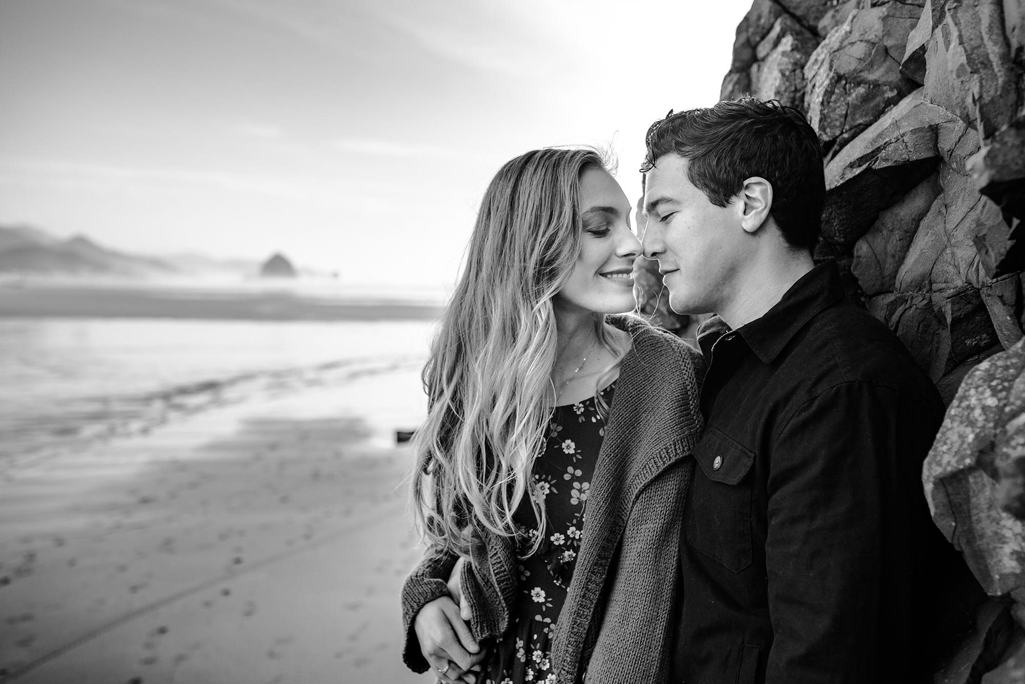 Engaged couple touching noses on Cannon Beach