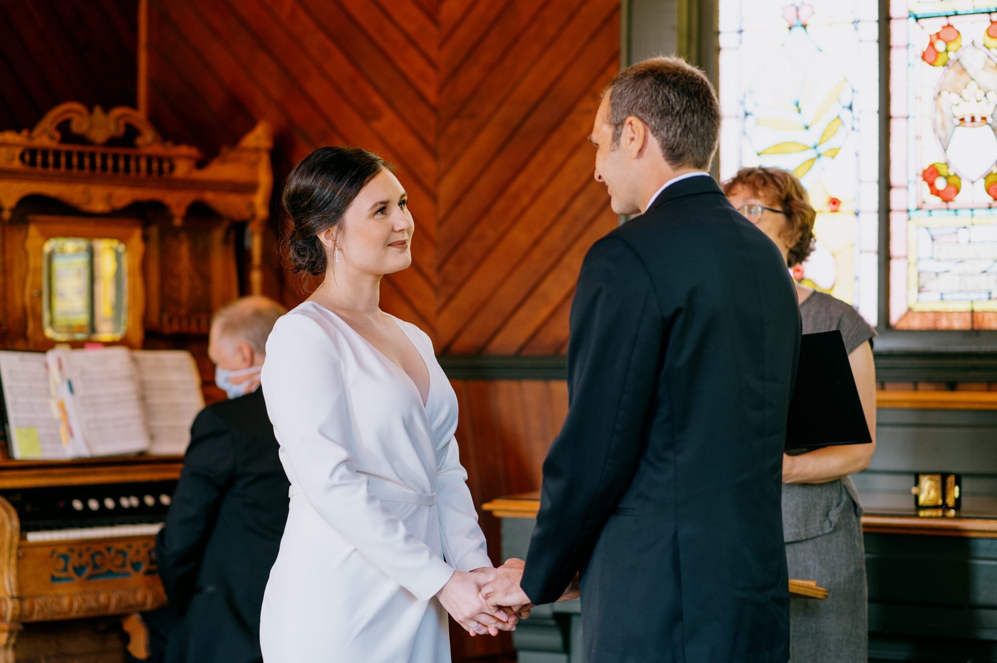 Bride looking at groom and holding hands during wedding ceremony at Oaks Pioneer Church