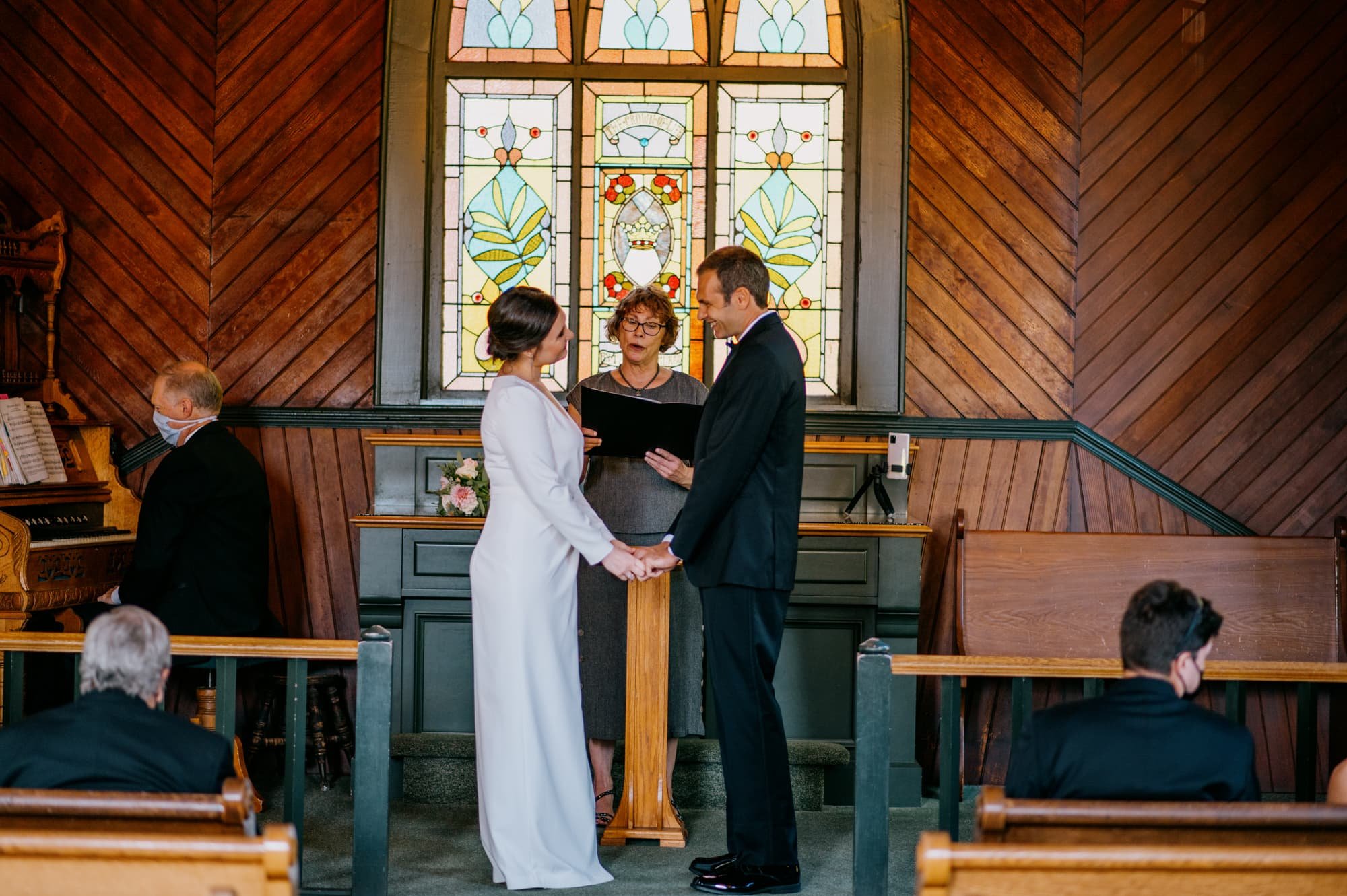 Bride and Groom during ceremony holding hands at altar with officiant in background