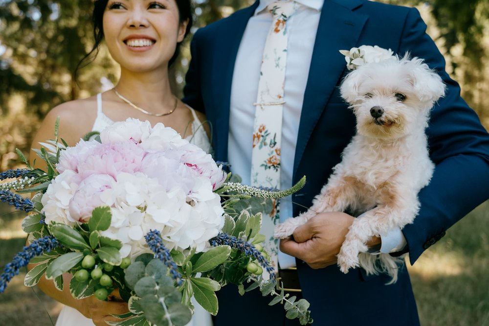 Detail of Bride and Groom holding bouquet and small dog