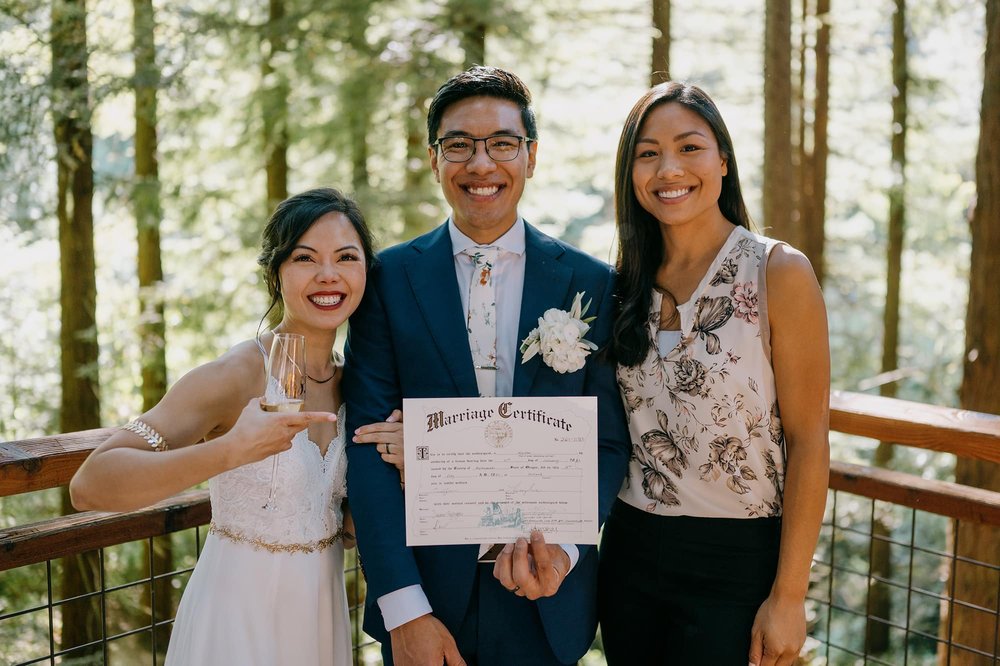 Bride and Groom holding marriage certificate with officiant standing next to them 