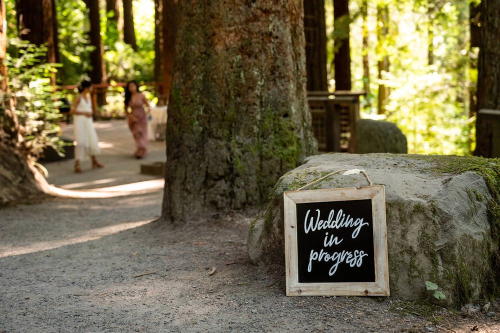 Wedding in progress sign resting on rock near Redwood Deck
