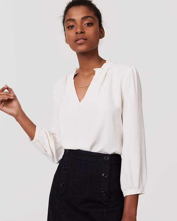 A plain white or cream blouse is a great option. Neutral colors suggest a softer more friendly personality. This particular blouse if from the Loft. You can purchase it here .