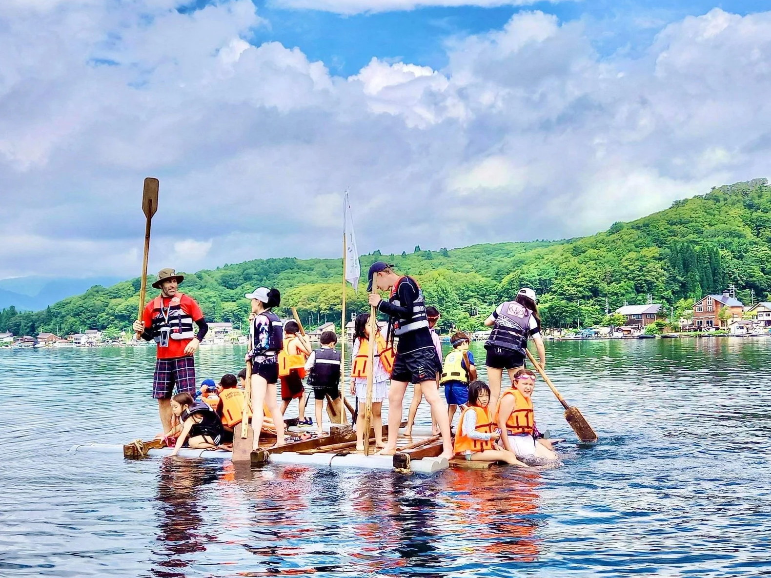 Kids and counsellors at summer camp doing a lake paddling team work challenge