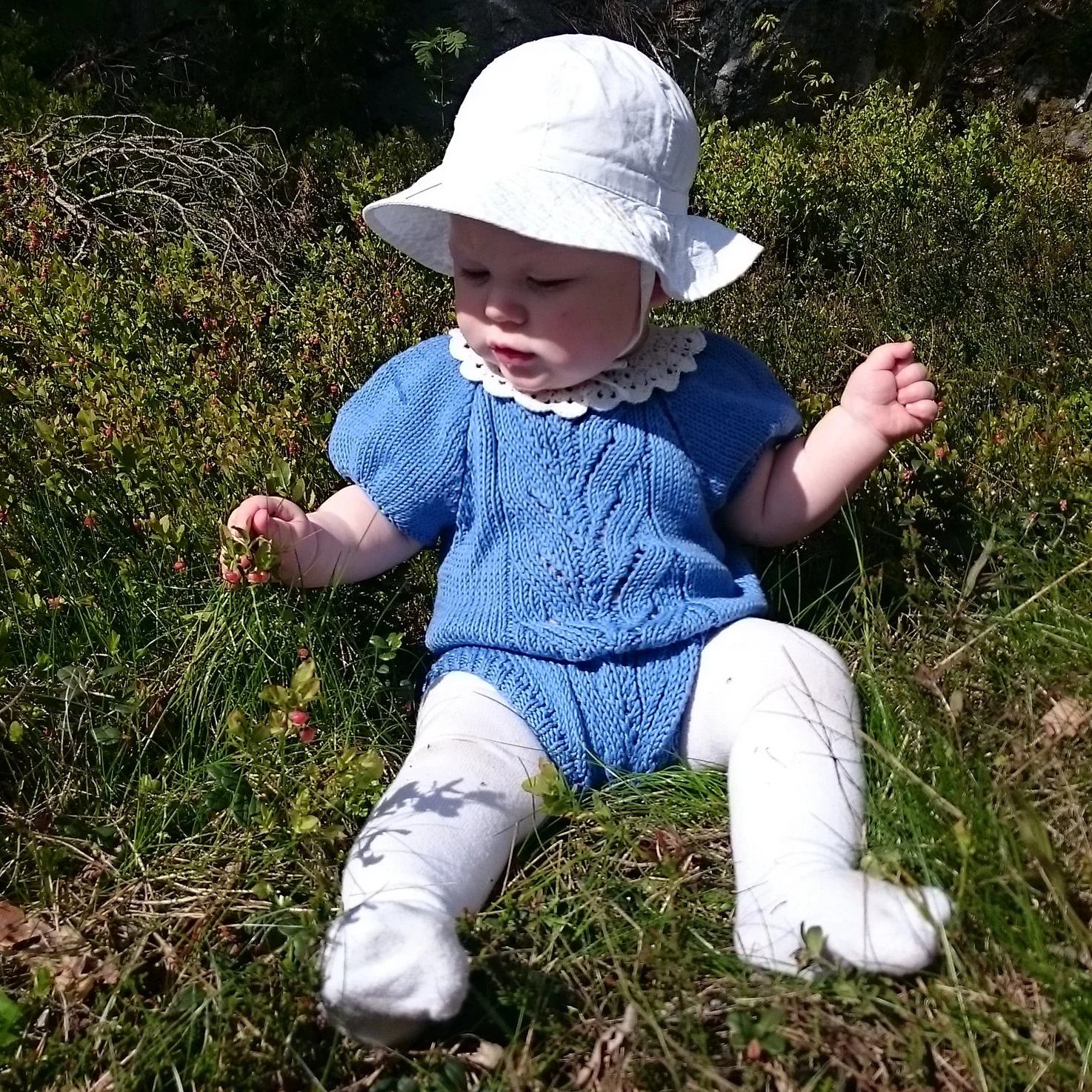 Vesle Tiril er en nydelig drakt med stort grenmønster foran, puffermer og raglanfelling. Overraskende enkel å strikke og kan brukes med body og strømpebukse under når været blir kaldere!