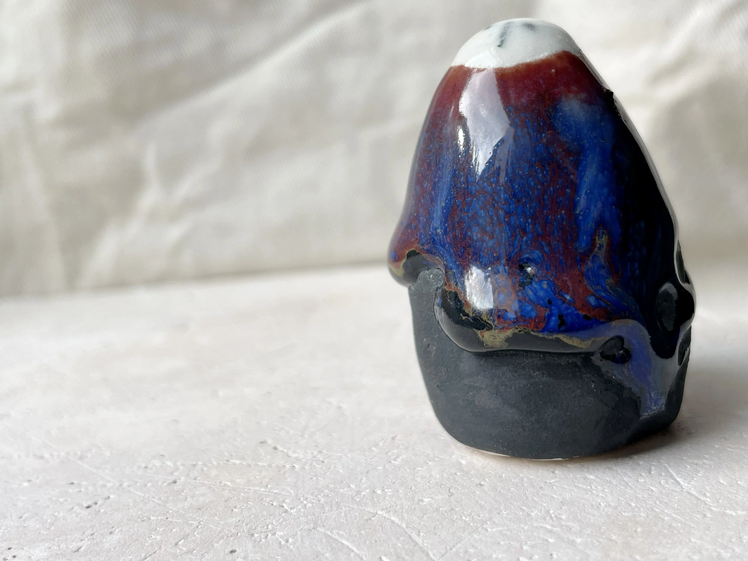 black, brown, red, blue and green handmade figurative ceramic sculpture with matte and glossy floating glaze